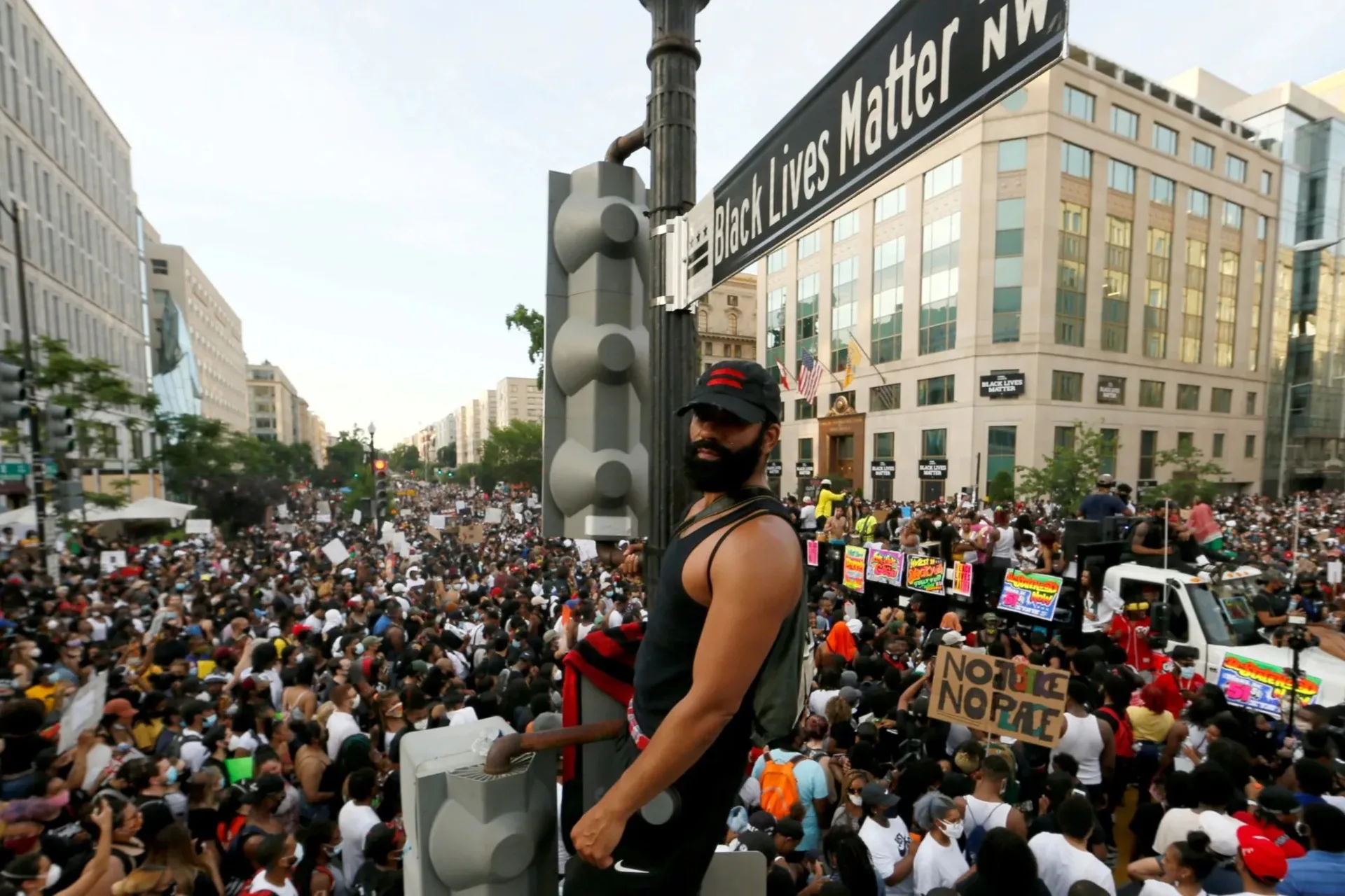 Man on sign post in front of protest crowd