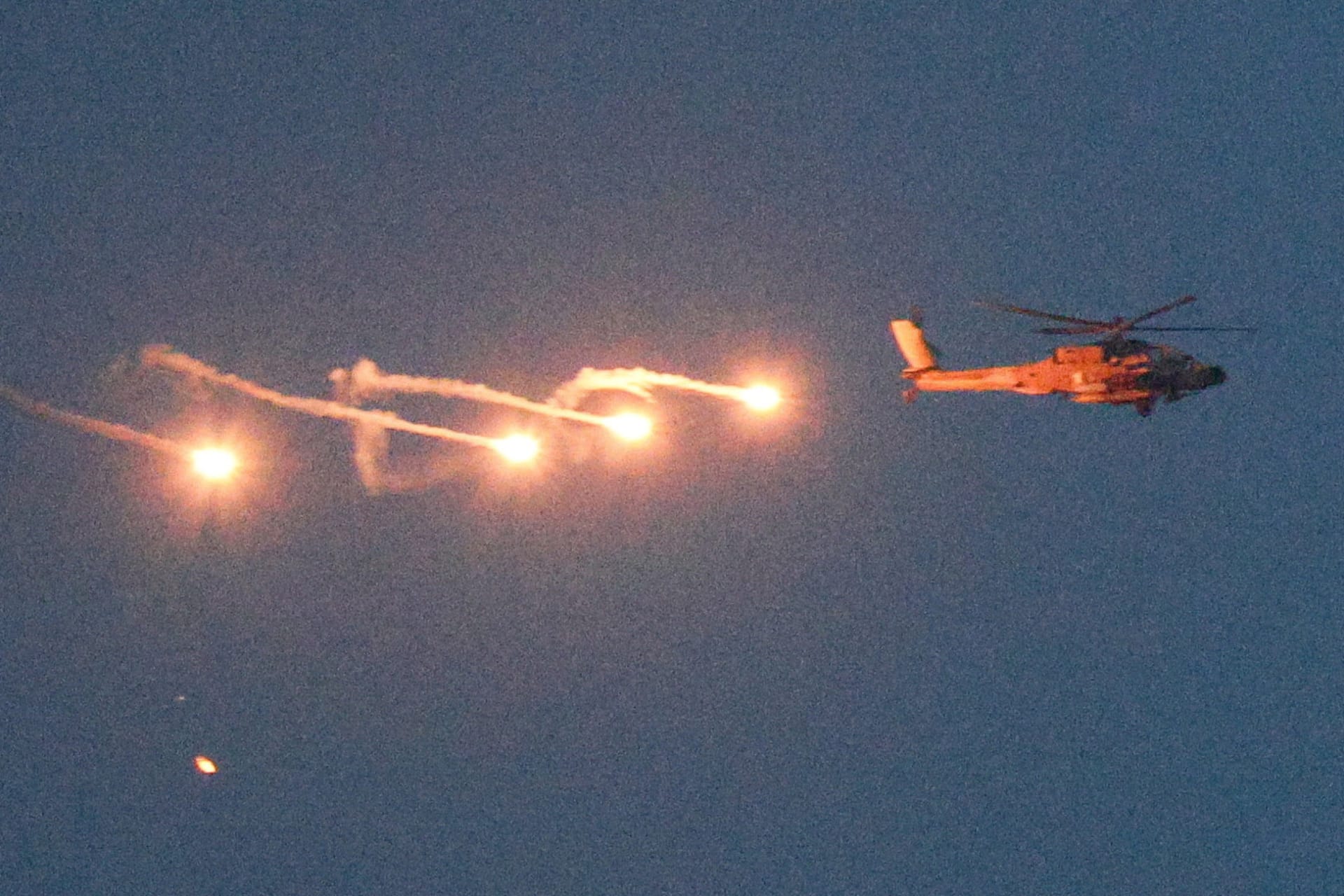 An Israeli helicopter releases flares as it flies over Lebanon, as seen from the Israeli side of the border with Lebanon