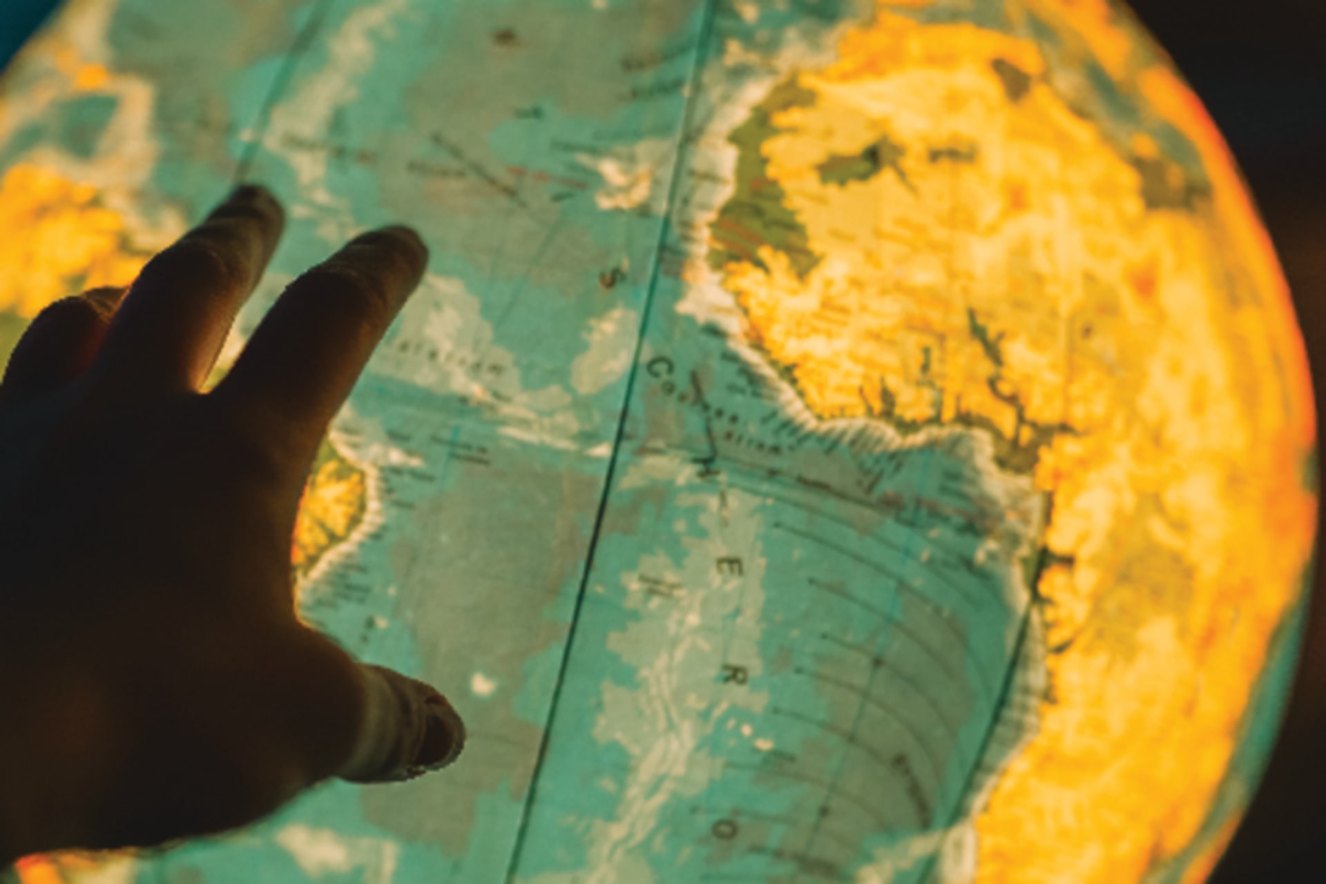 A hand reaching for an illuminated globe