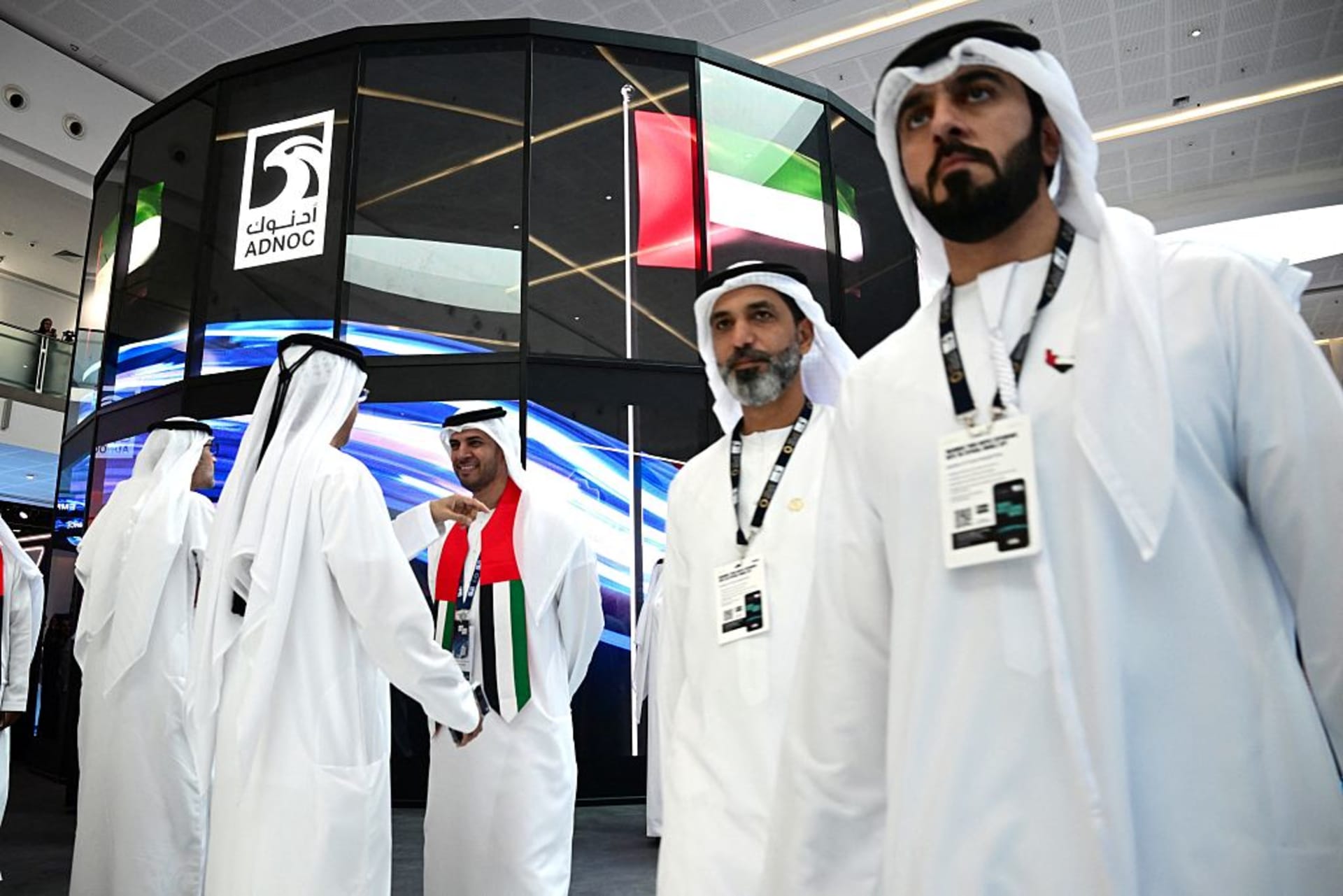 Guests stand at the booth of the Abu Dhabi National Oil Company (ADNOC), during the Abu Dhabi International Petroleum Exhibition & Conference (ADIPEC) in Abu Dhabi on November 3, 2025.