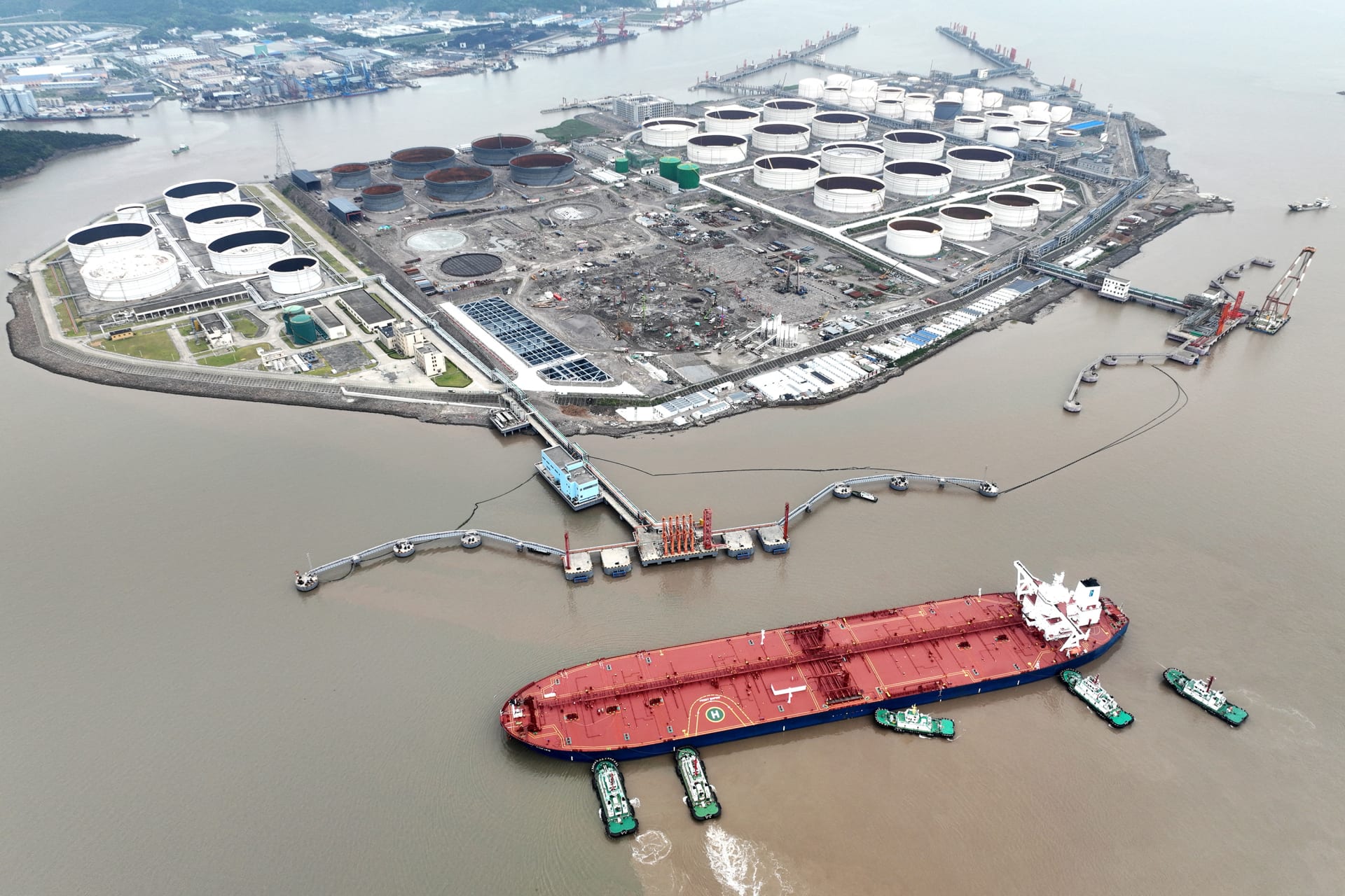 An aerial view shows tugboats helping a crude oil tanker to berth at an oil terminal, off Waidiao Island in Zhoushan, Zhejiang province, China July 18, 2022. cnsphoto via REUTERS