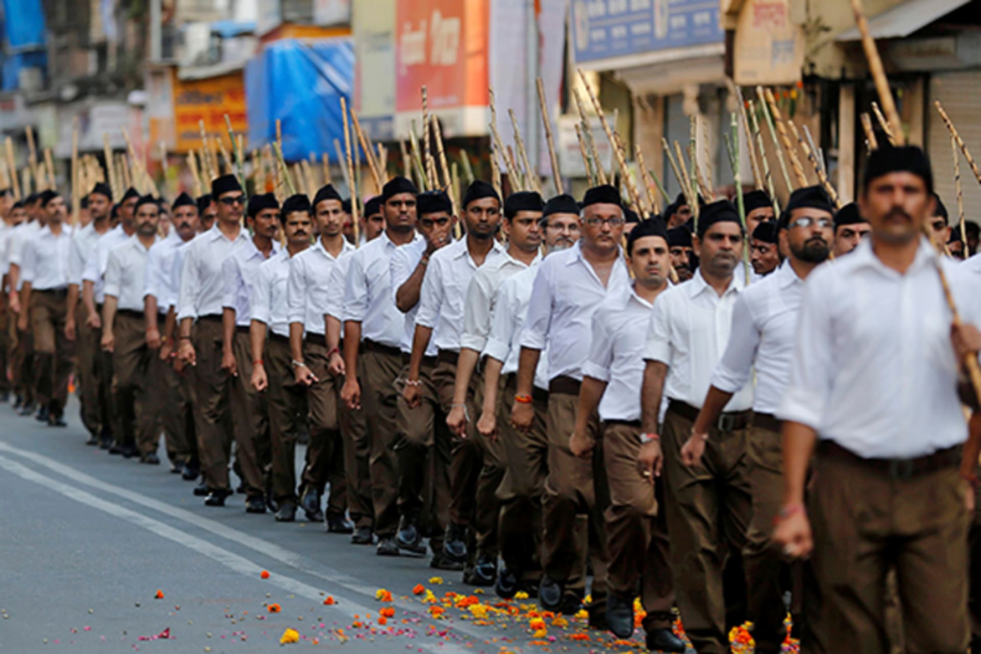 A man rides his bicycle past volunteers of the Hindu nationalist organisation Rashtriya Swayamsevak Sangh (RSS) taking part in the "Path-Sanchalan", or Route March, during celebrations to mark the Vijaya Dashmi or Dussehra in Mumbai, India.