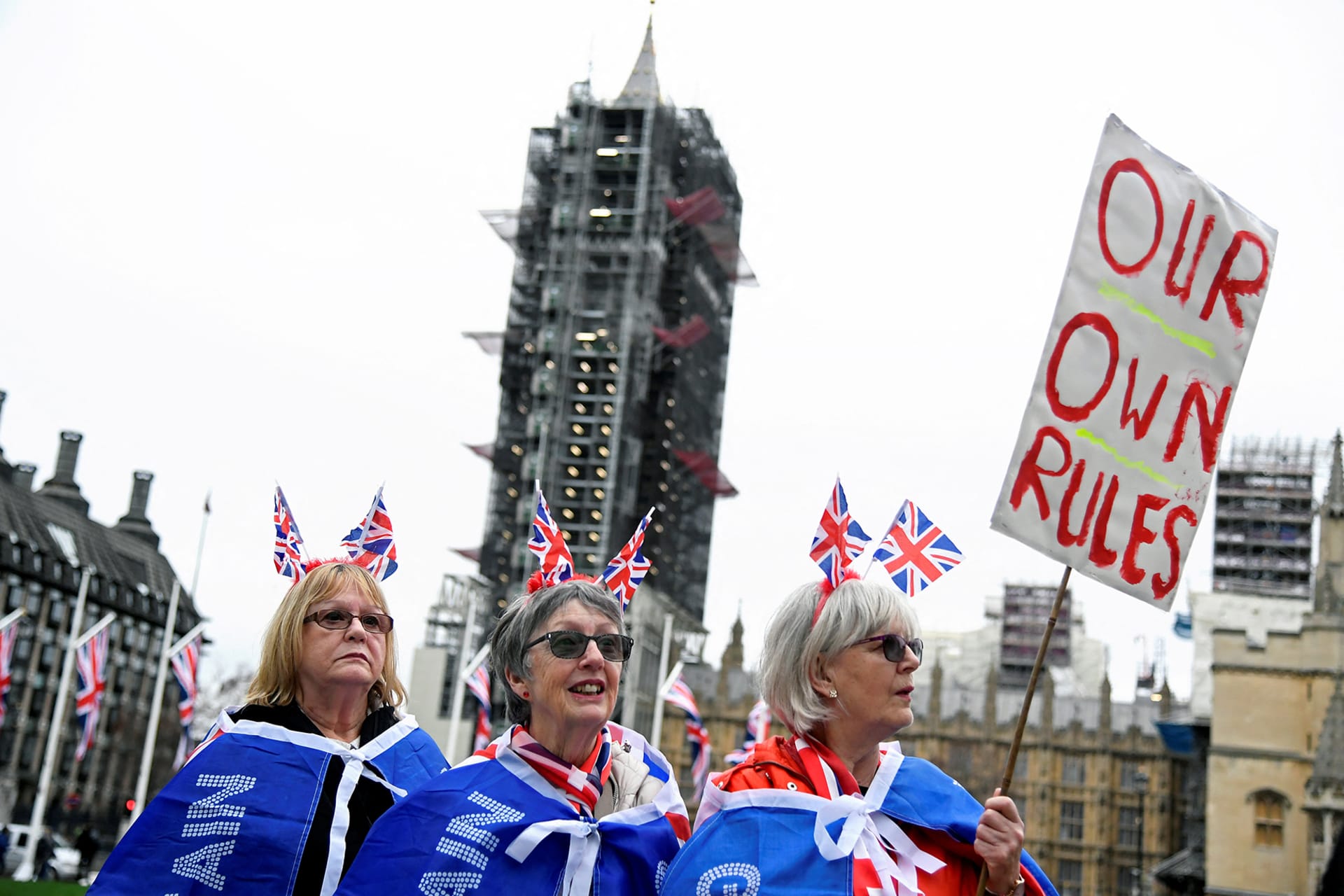 Pro-Brexit supporters wear British flags while one holds a placard that reads "Our own rules".