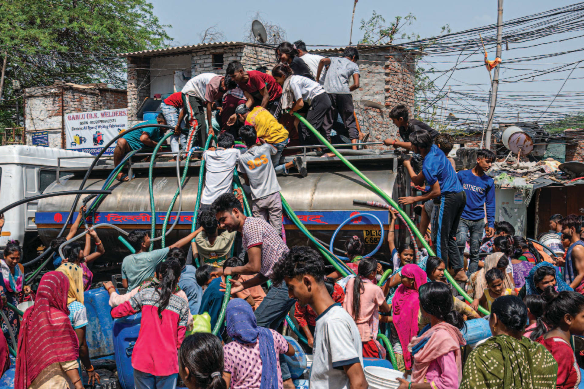 People climb atop a water tanker with pipes to fill their containers as a heat wave drives up demand and causes shortages, with the government delivering water by truck in New Delhi, India, on June 15, 2024.