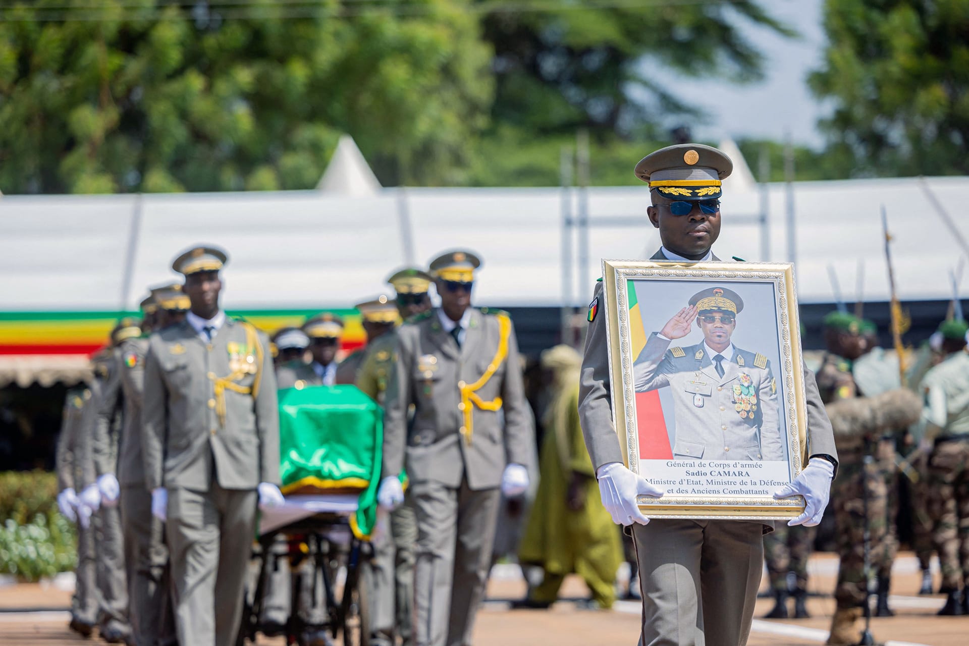 Malian soldiers march in uniform while carrying a portrait and the coffin of Defense Minister Camara.