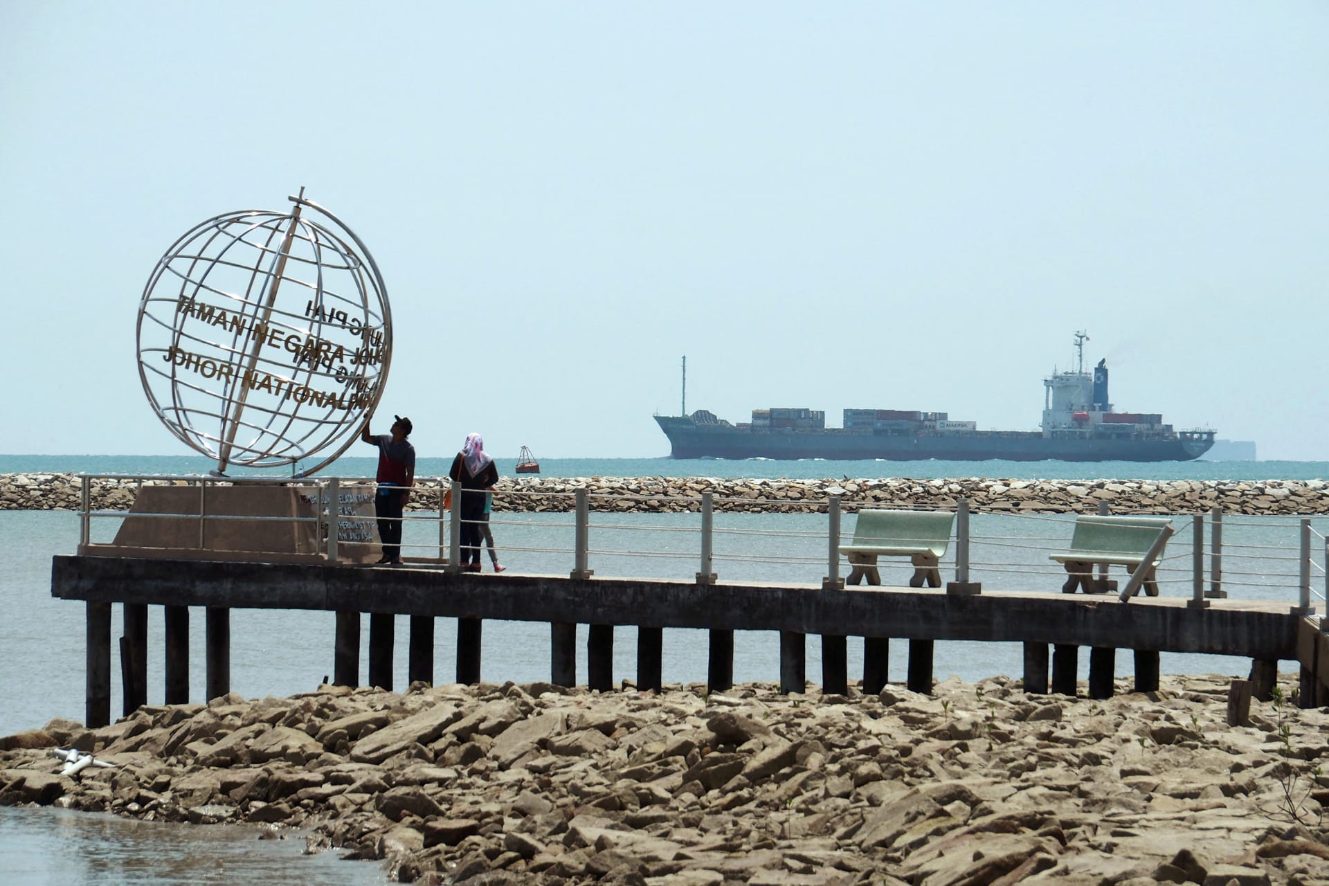 <p>A container ship enters the Singapore Strait for the Strait of Malacca, as tourists stand at mainland Asia’s southern most point in Johor, Malaysia on November 12, 2016.</p>
