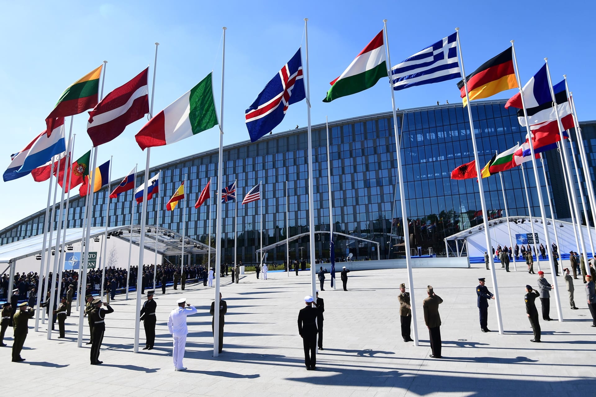 Officials and military personnel stand beneath flags as they attend the NATO (North Atlantic Treaty Organization) summit ceremony at the NATO headquarters, in Brussels, on May 25, 2017.