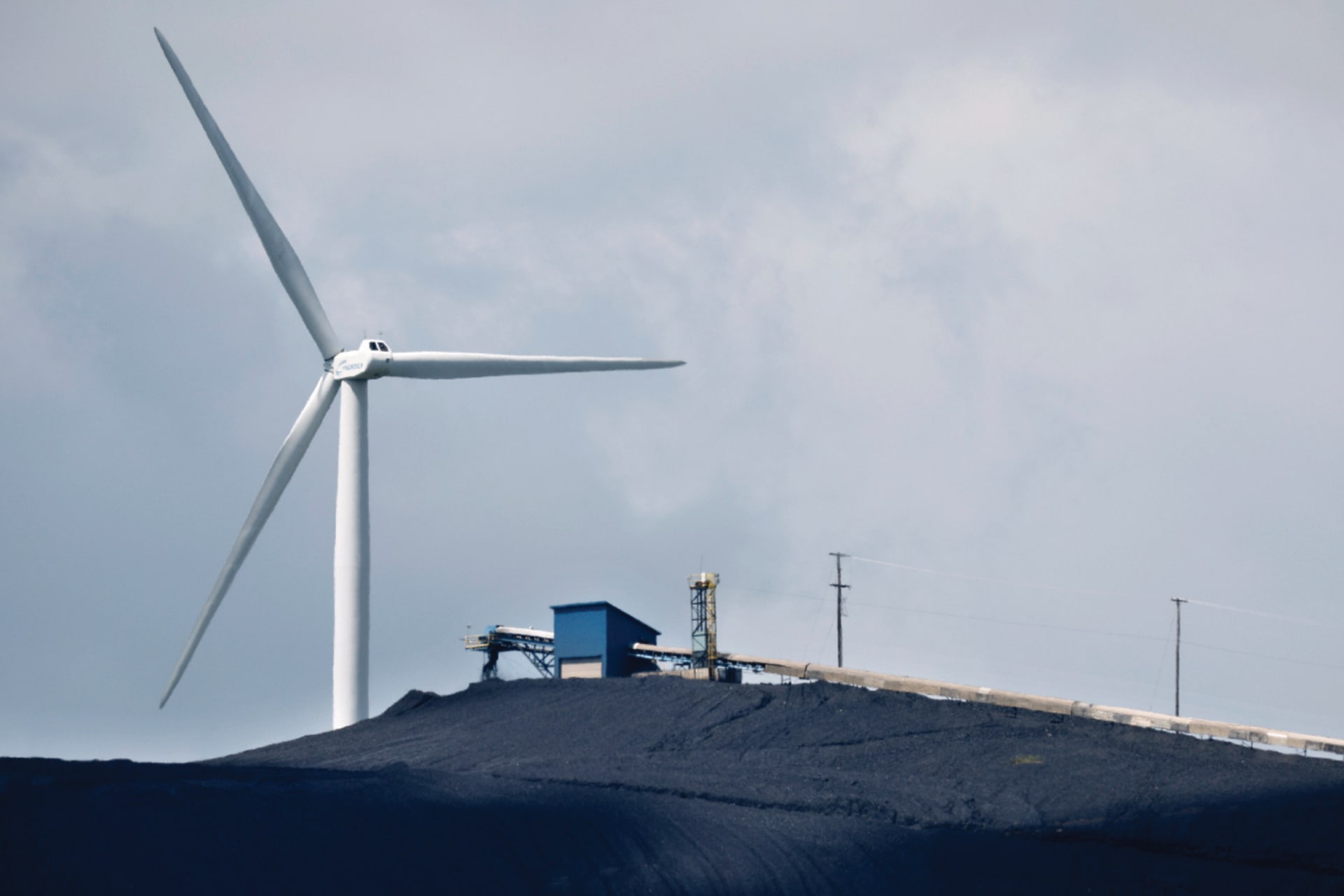 A turbine from a wind farm spins behind the Mettiki Coal processing plant in Oakland, Maryland