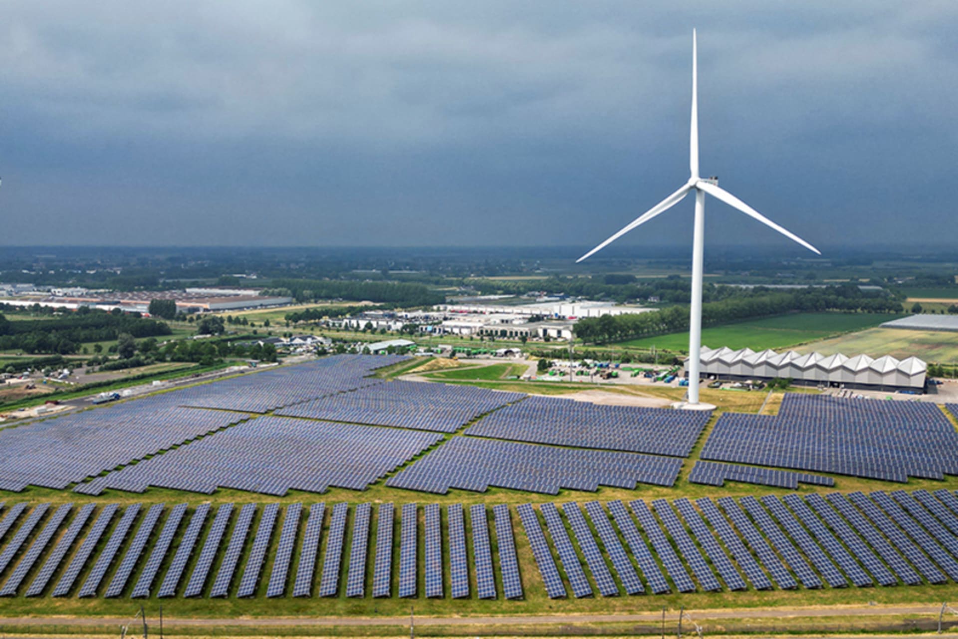 Two wind turbines are positioned amidst many solar panels