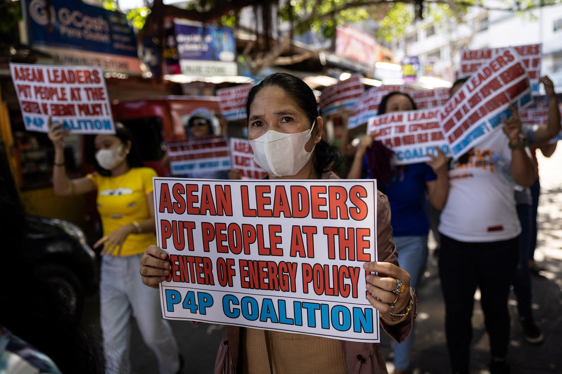 A woman holds up a protest sign reading "ASEAN leaders put people at the center of energy policy P4P coalition".