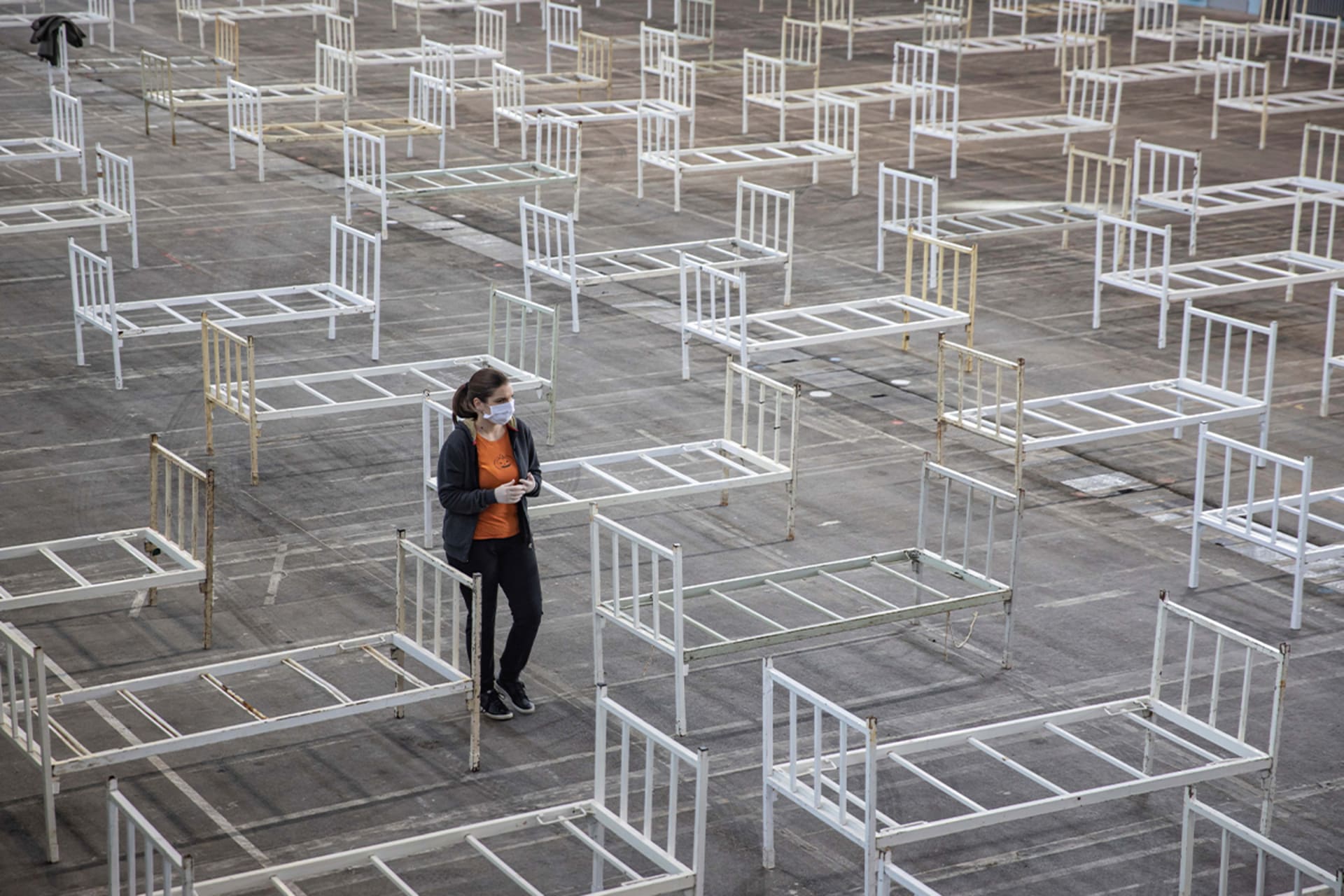 <p>A volunteer walks as the Serbian military sets up beds to accommodate people who suffer mild symptoms of coronavirus disease (COVID-19) in Novi Sad, Serbia on March 27, 2020.</p>