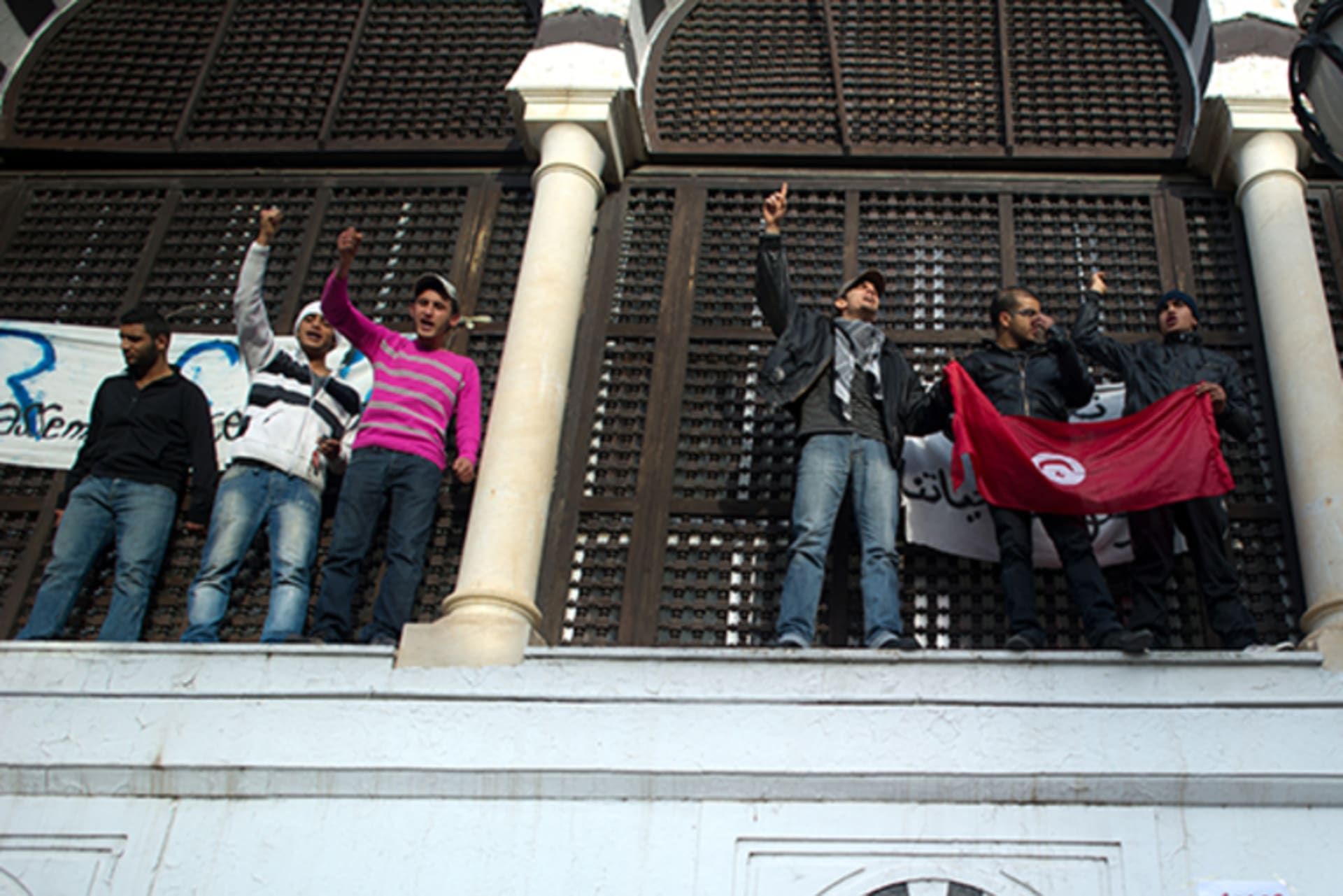 Protesters hold a flag of Tunisia as others shout slogans during a demonstration in a street of central Tunis on January 21, 2011.
