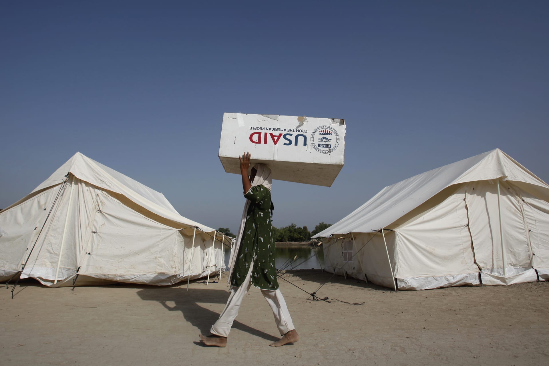 A woman displaced by floods uses a box from the U.S. Agency for International Development to move her belongings in Dadu, Pakistan, on October 10, 2010.