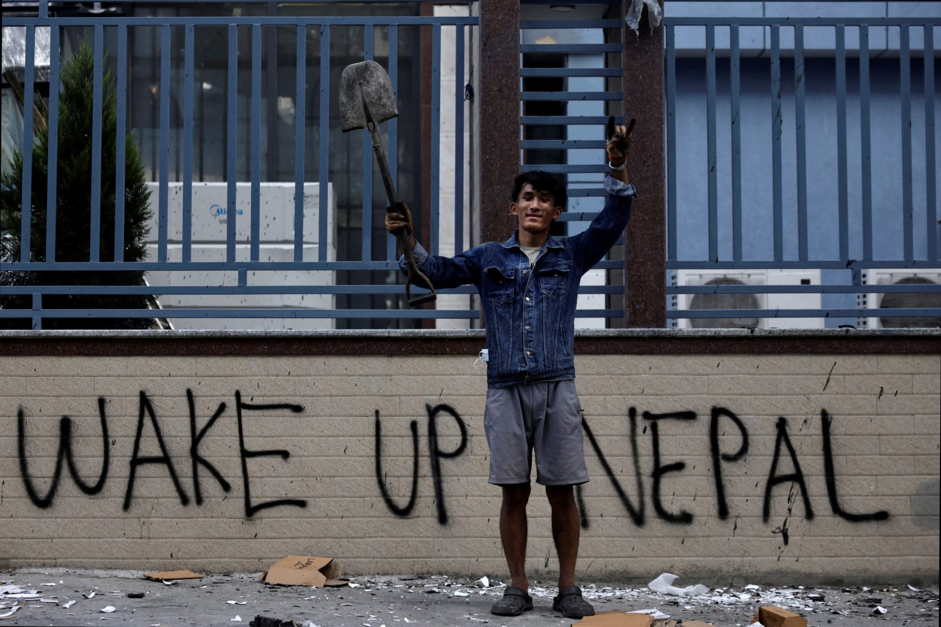 <p>20-year-old protestor Sabin Tamang holds up a shovel while posing for a photograph next to graffiti as he takes part in a cleaning campaign on September 10, 2025 following deadly anti-corruption protests in Kathmandu, Nepal.</p>
