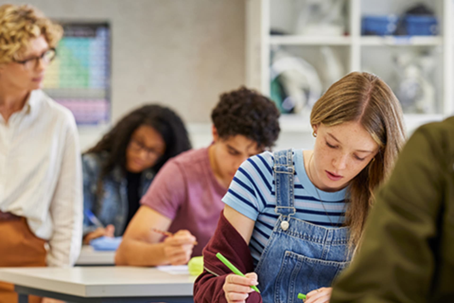 Female teacher observes students during exam at high school stock photo