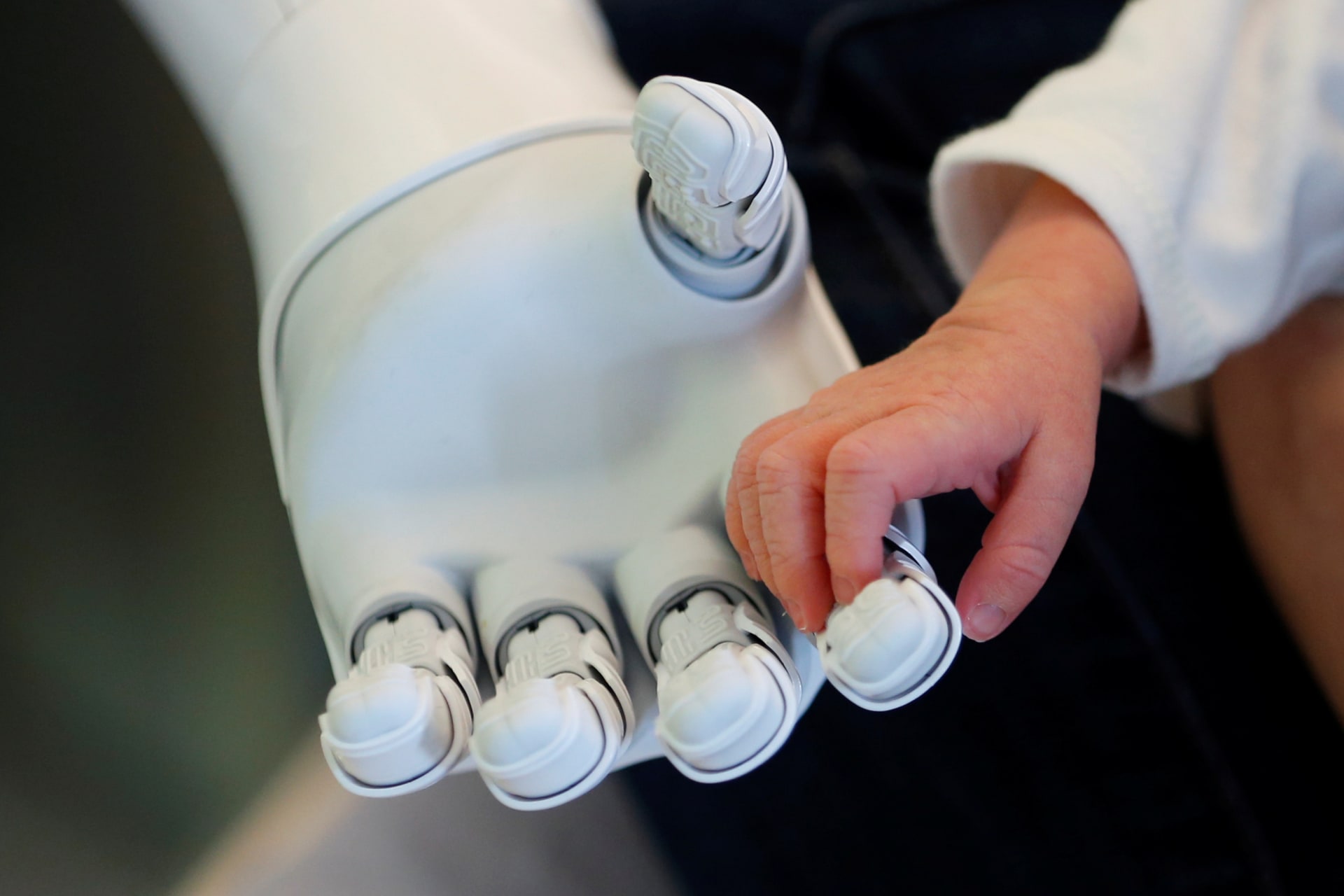 A robot holds the hand of a baby.