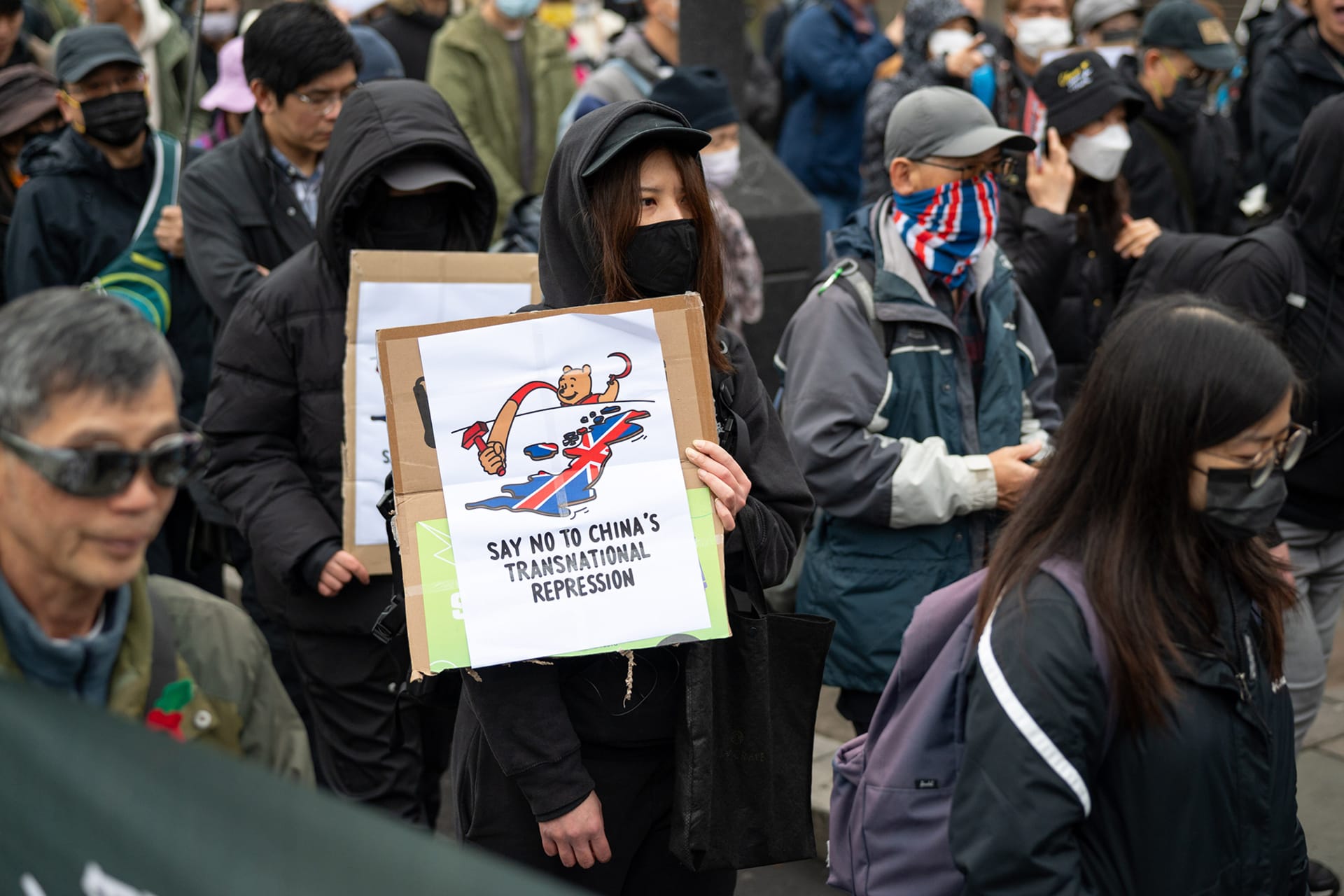 A protester holds a placard saying "Say no to China's transnational repression" during a demonstration.