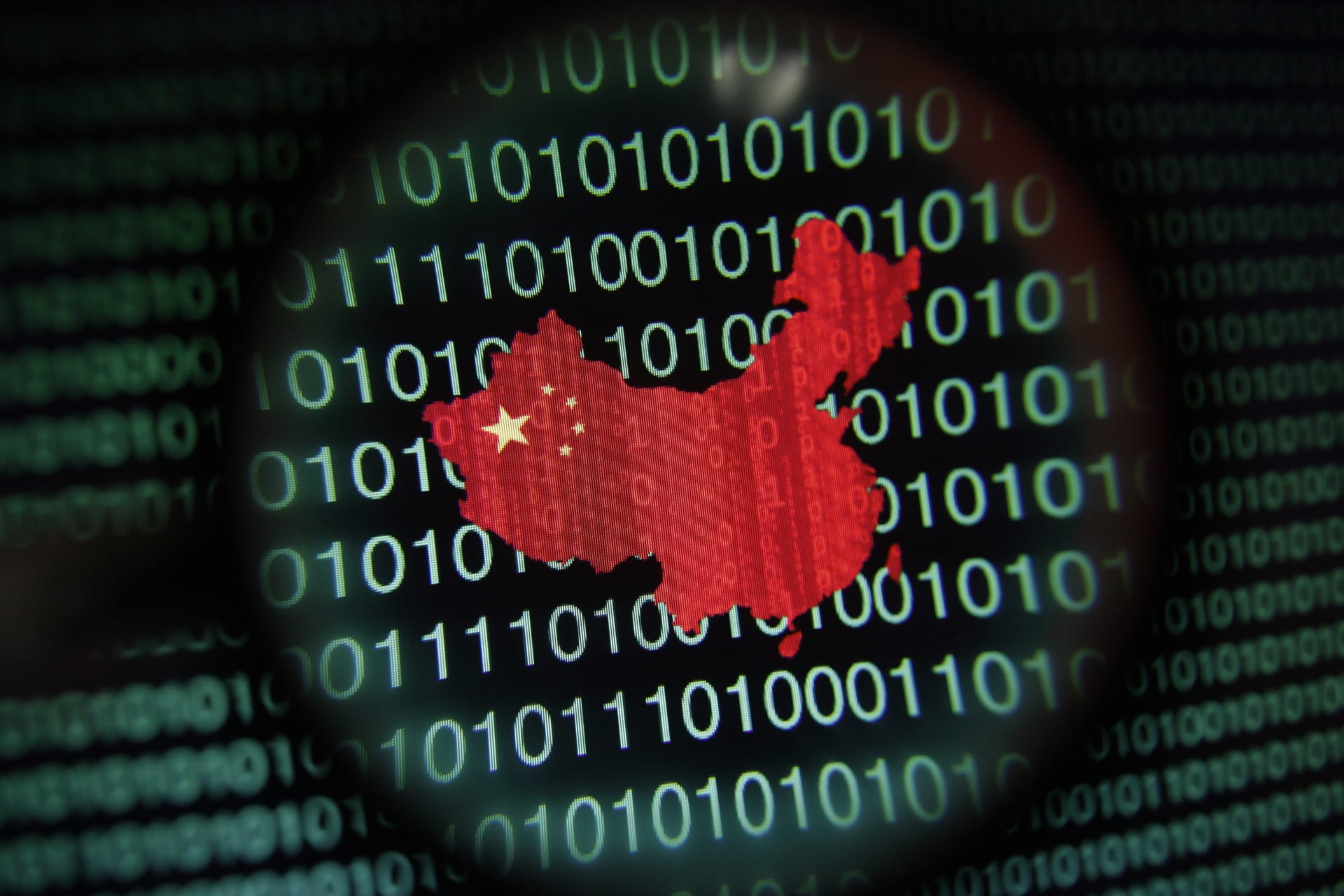 The shape of China with the country flag overlaid can be seen zoomed in through a magnifying class. There are ones and zeroes in the background.