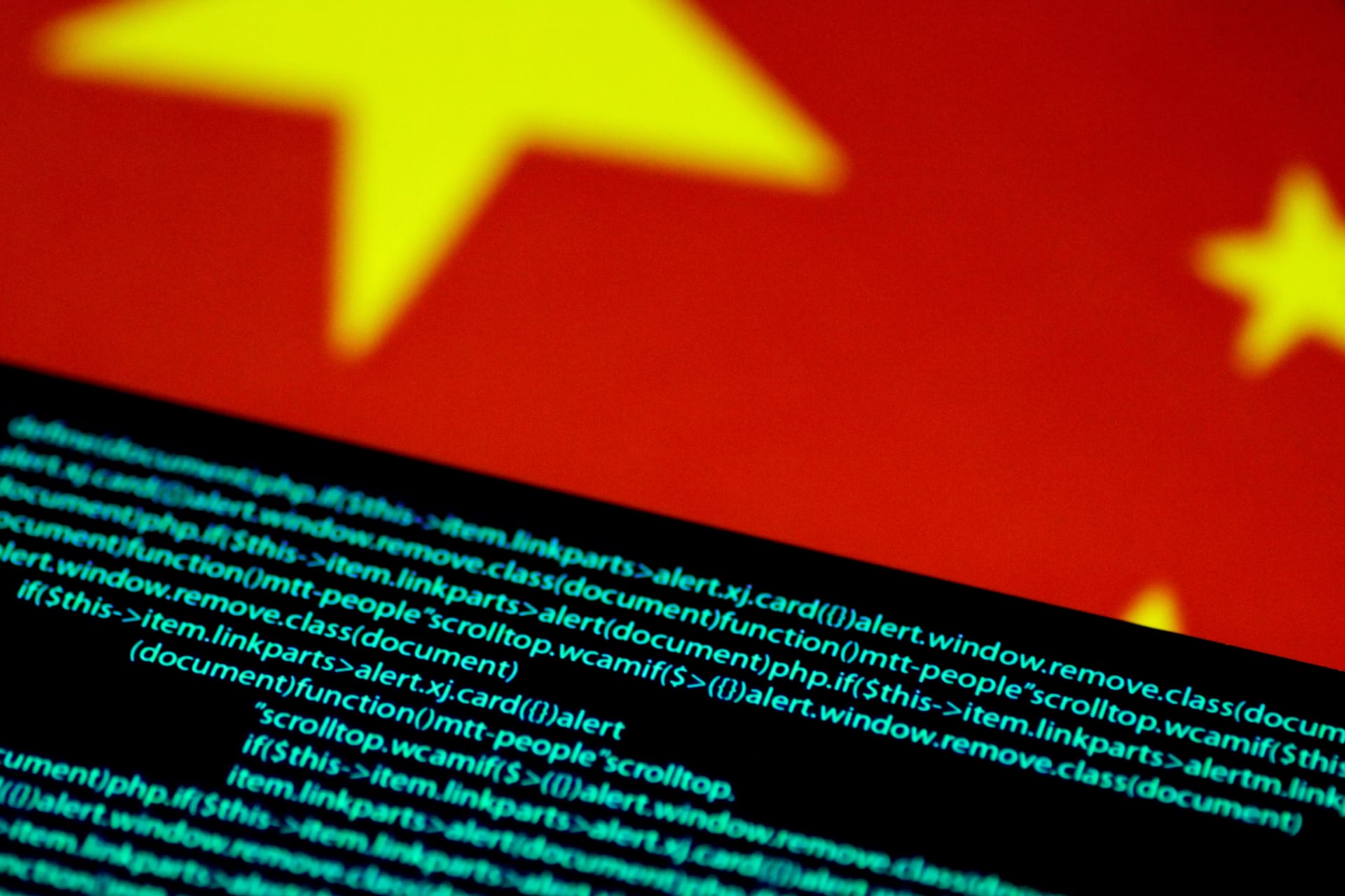 The Chinese flag can be seen in the background, blurry, as lines of code are in the foreground.
