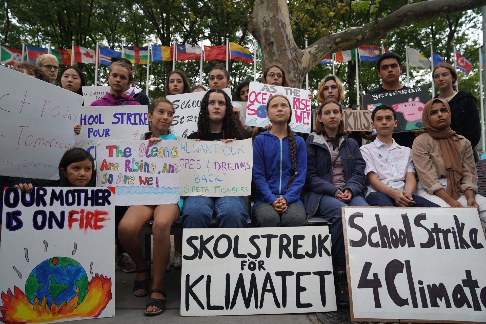 Students holding signs at a climate strike. Greta Thunberg is seated at the front.
