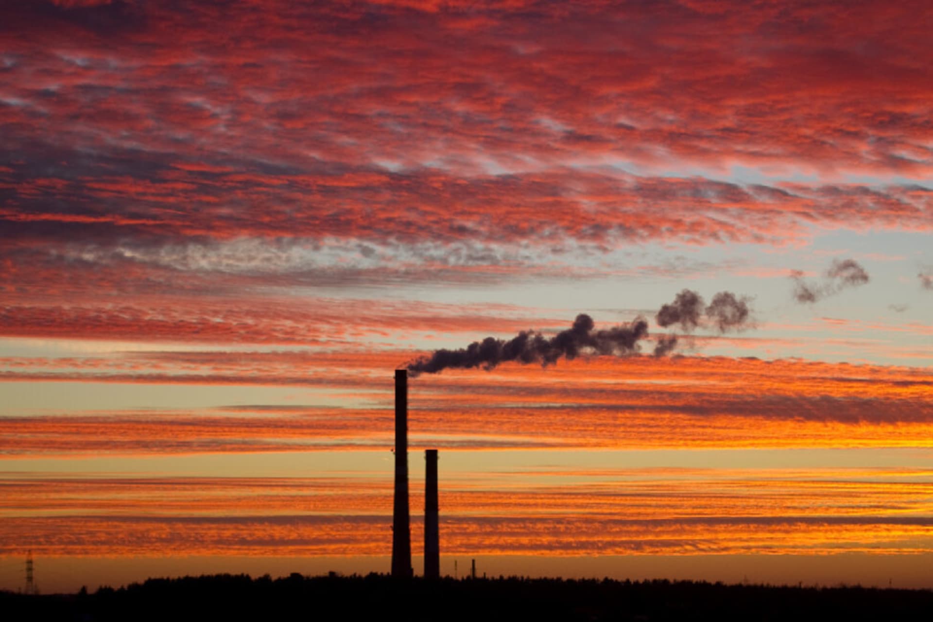 A sunset behind two smokestacks.