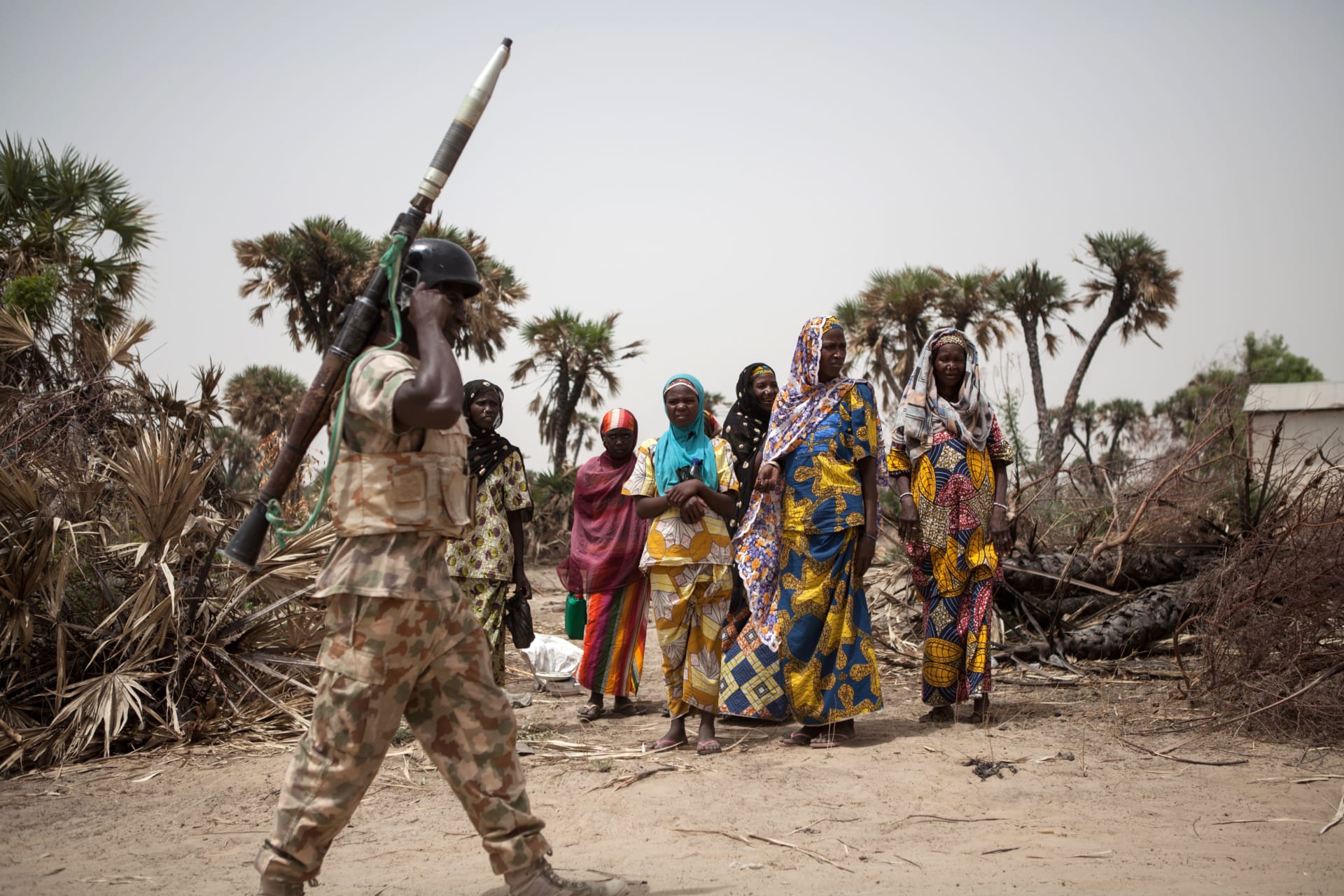 A militant carrying an RPG in front of a group of Nigerian villagers.
