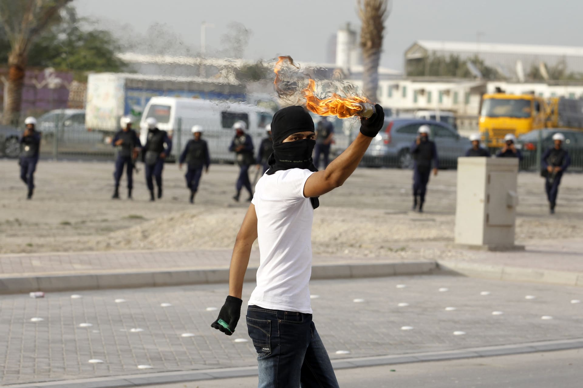 A person with their face covered holding up a Molotov cocktail in Bahrain.