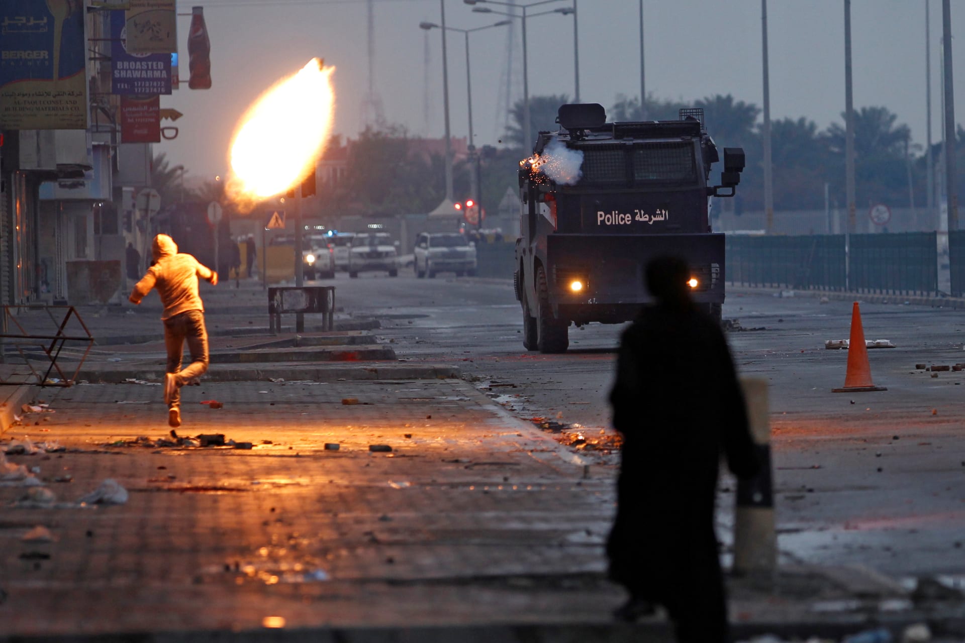A person throwing a Molotov cocktail at a police truck.