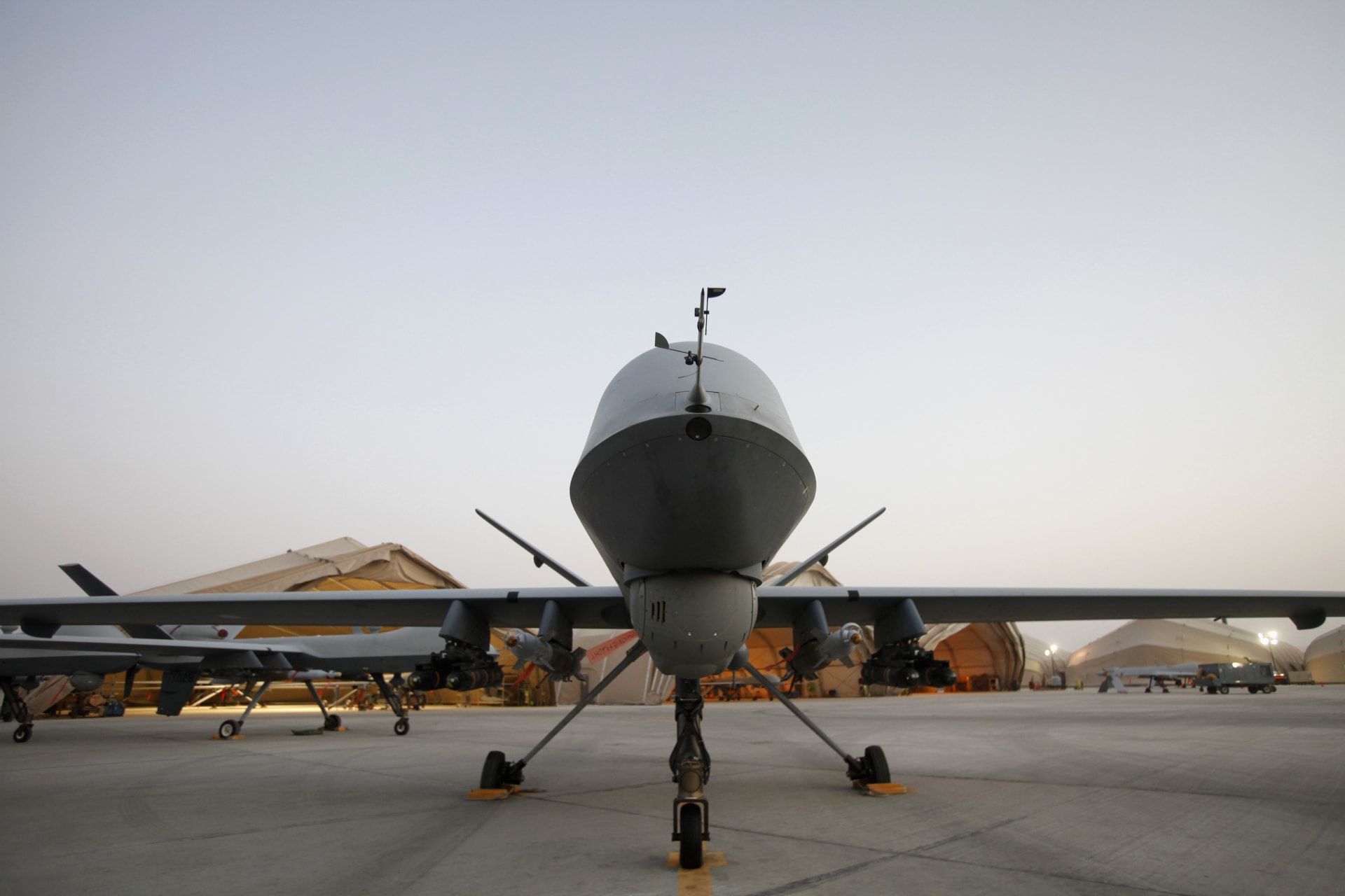 A drone sitting in an airfield among several other vehicles.