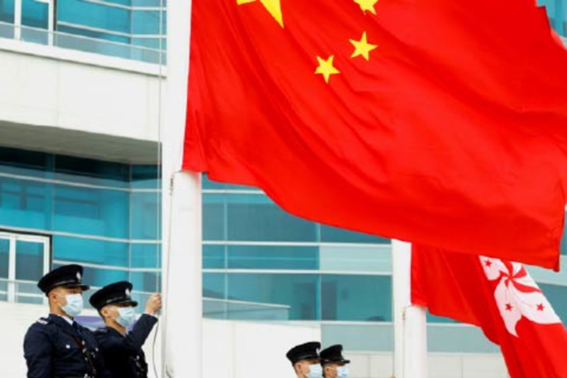 Chinese policemen raise a Chinese flag.