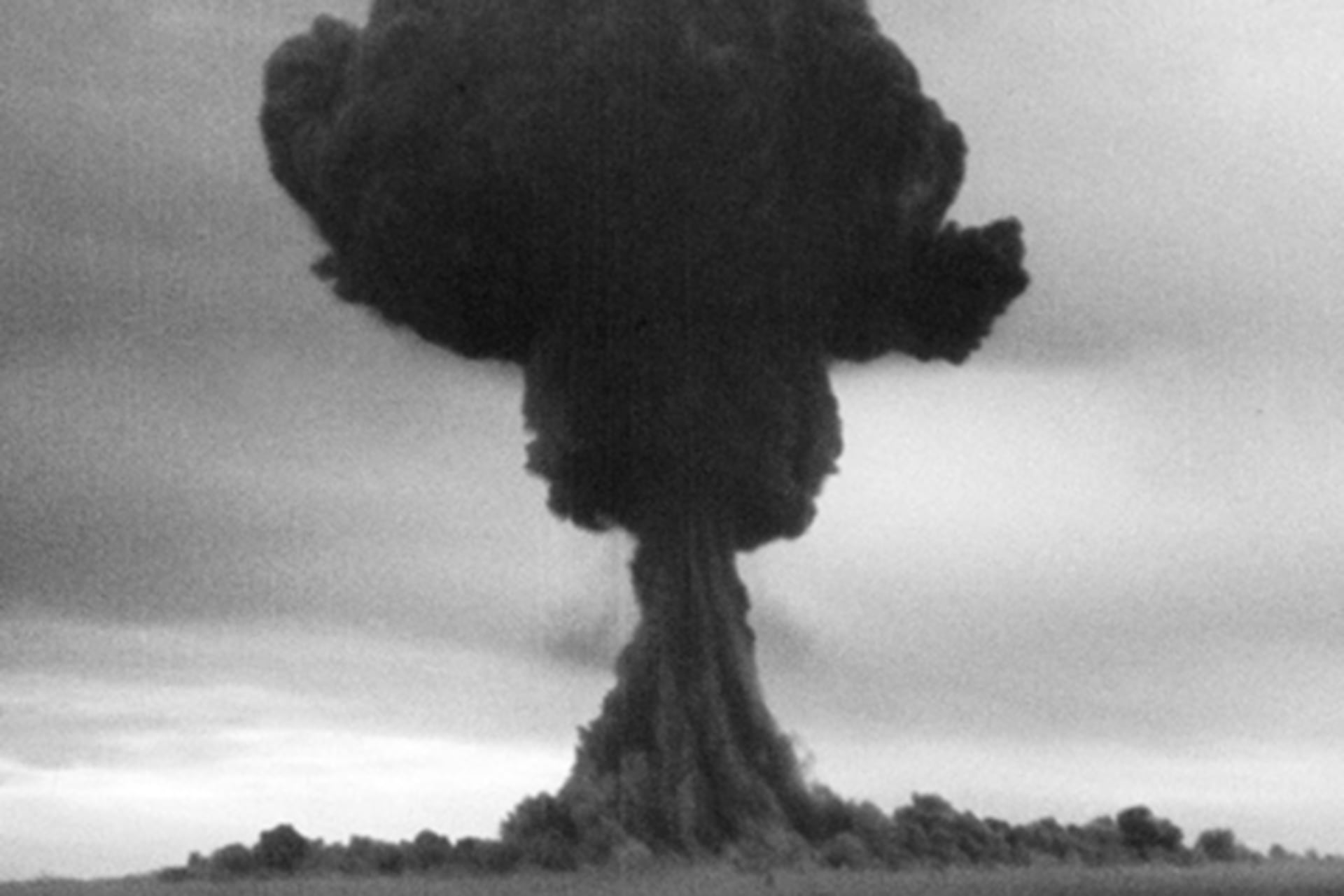 A black and white photograph of a large, black mushroom cloud.