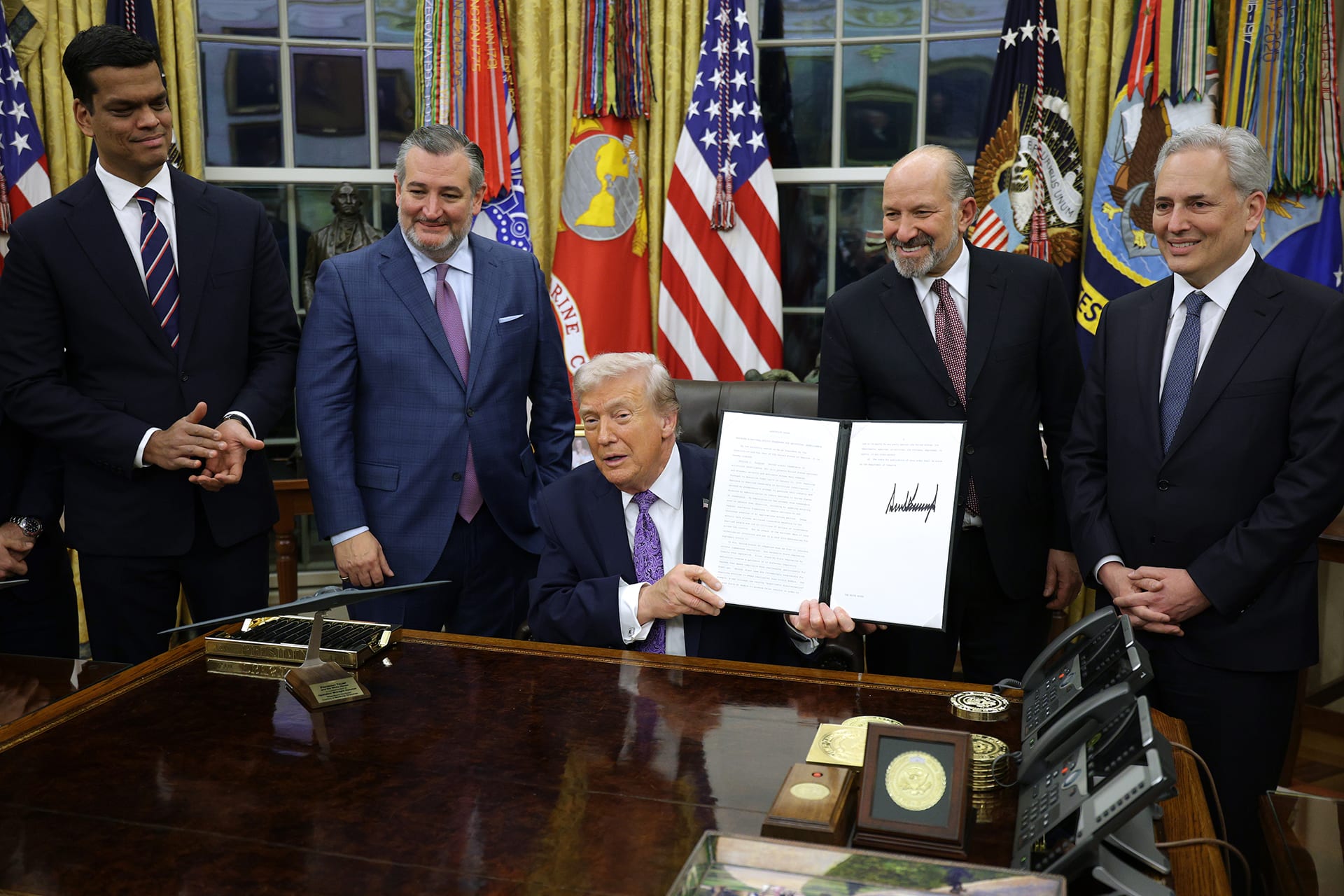 U.S. President Donald Trump displays a signed executive order as (2nd L-R) U.S. Sen. Ted Cruz (R-TX), Commerce Secretary Howard Lutnick and White House artificial intelligence (AI) and crypto czar David Sacks look on in the Oval Office of the White House on December 11, 2025 in Washington, DC.