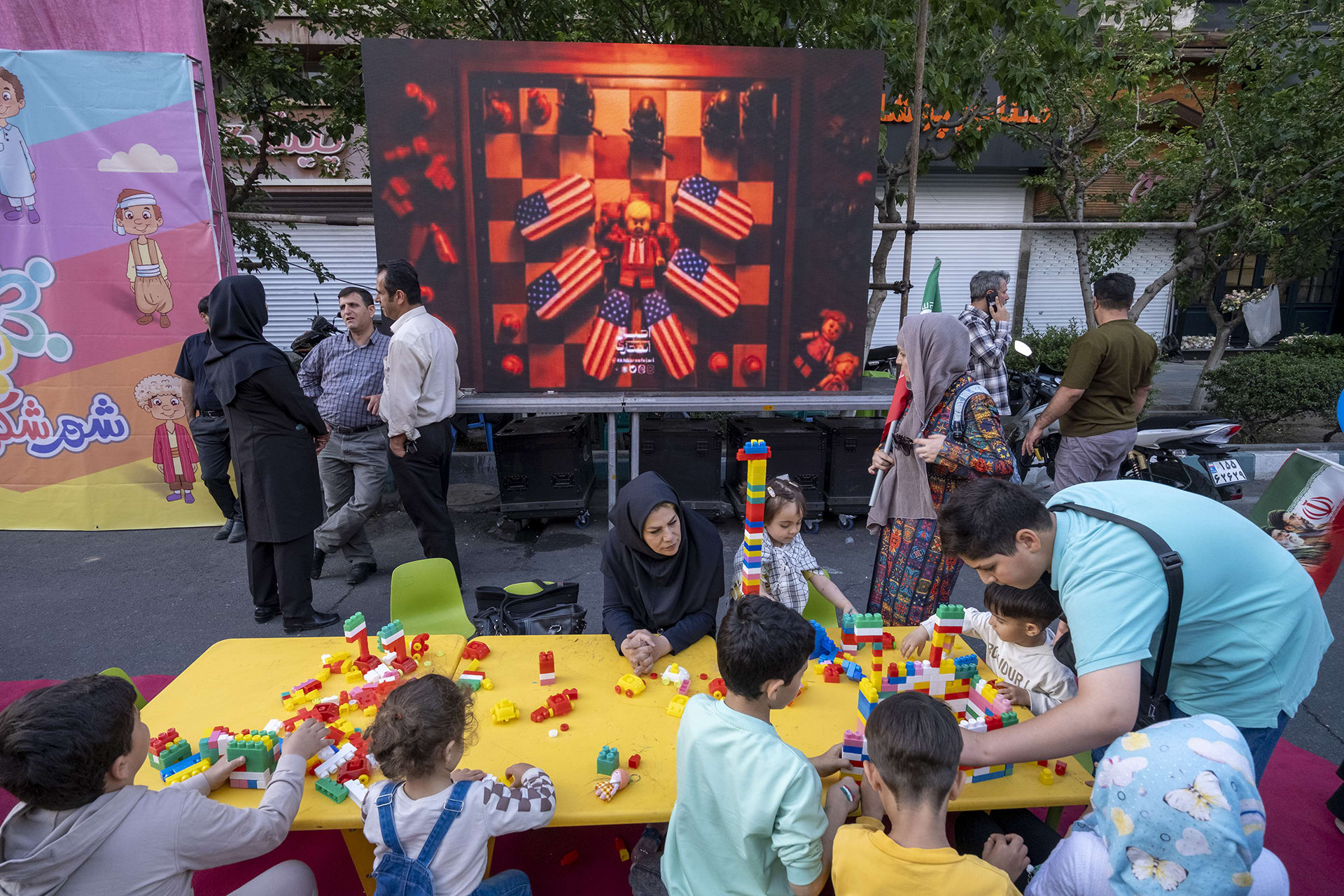 Iranian children play as an animation featuring an effigy of U.S. President Donald Trump and coffins of American soldiers is displayed during a state-run religious rally in downtown Tehran, Iran, on April 29, 2026.