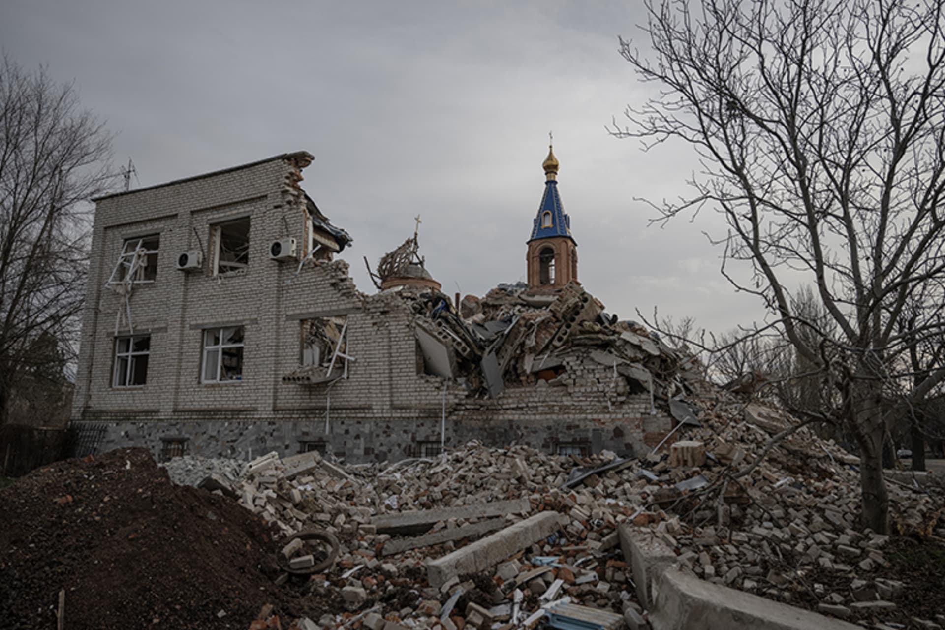 A damaged building in front of a church steeple in Ukraine.
