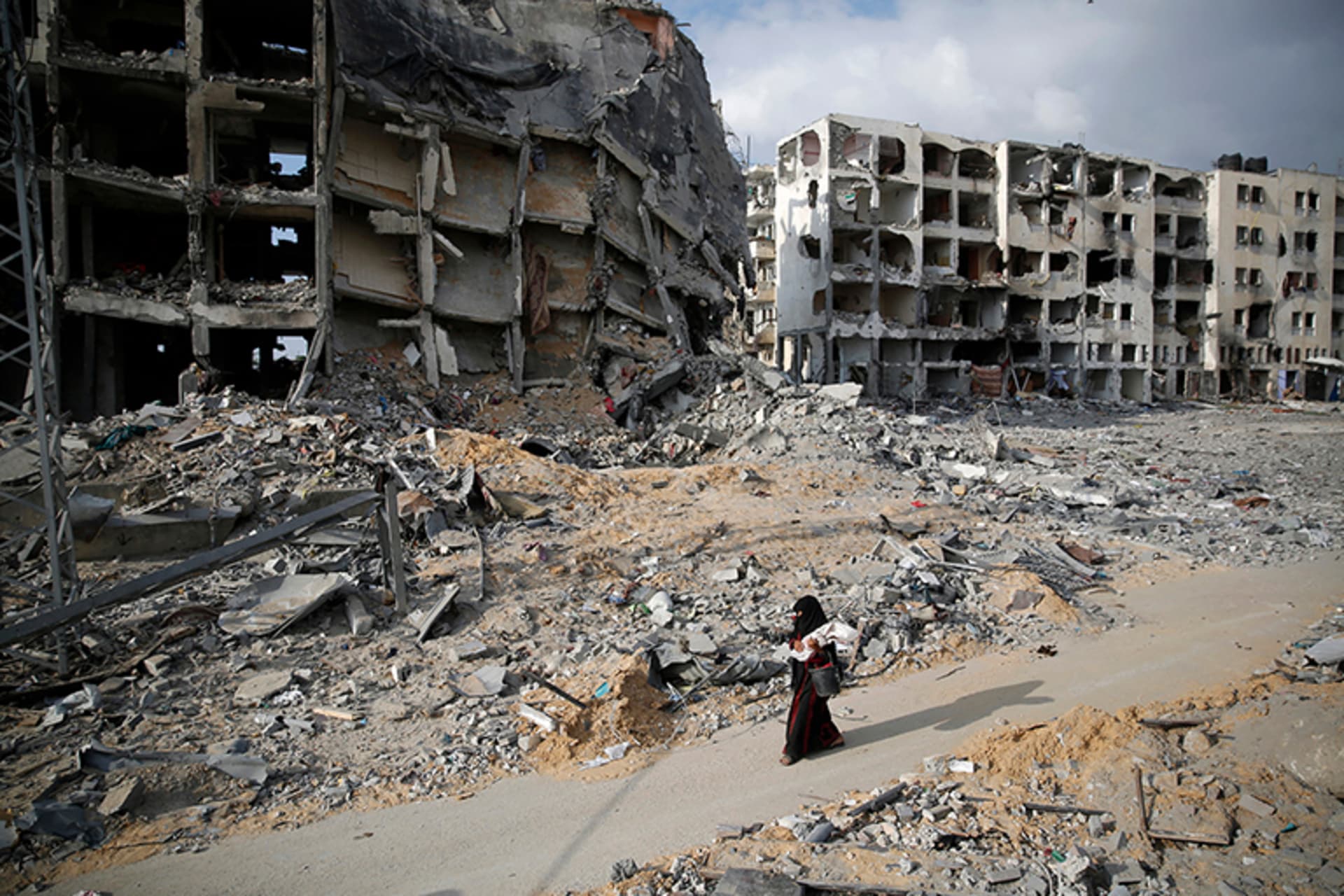A Palestinian woman walks past buildings destroyed by what police said were Israeli air strikes and shelling.
