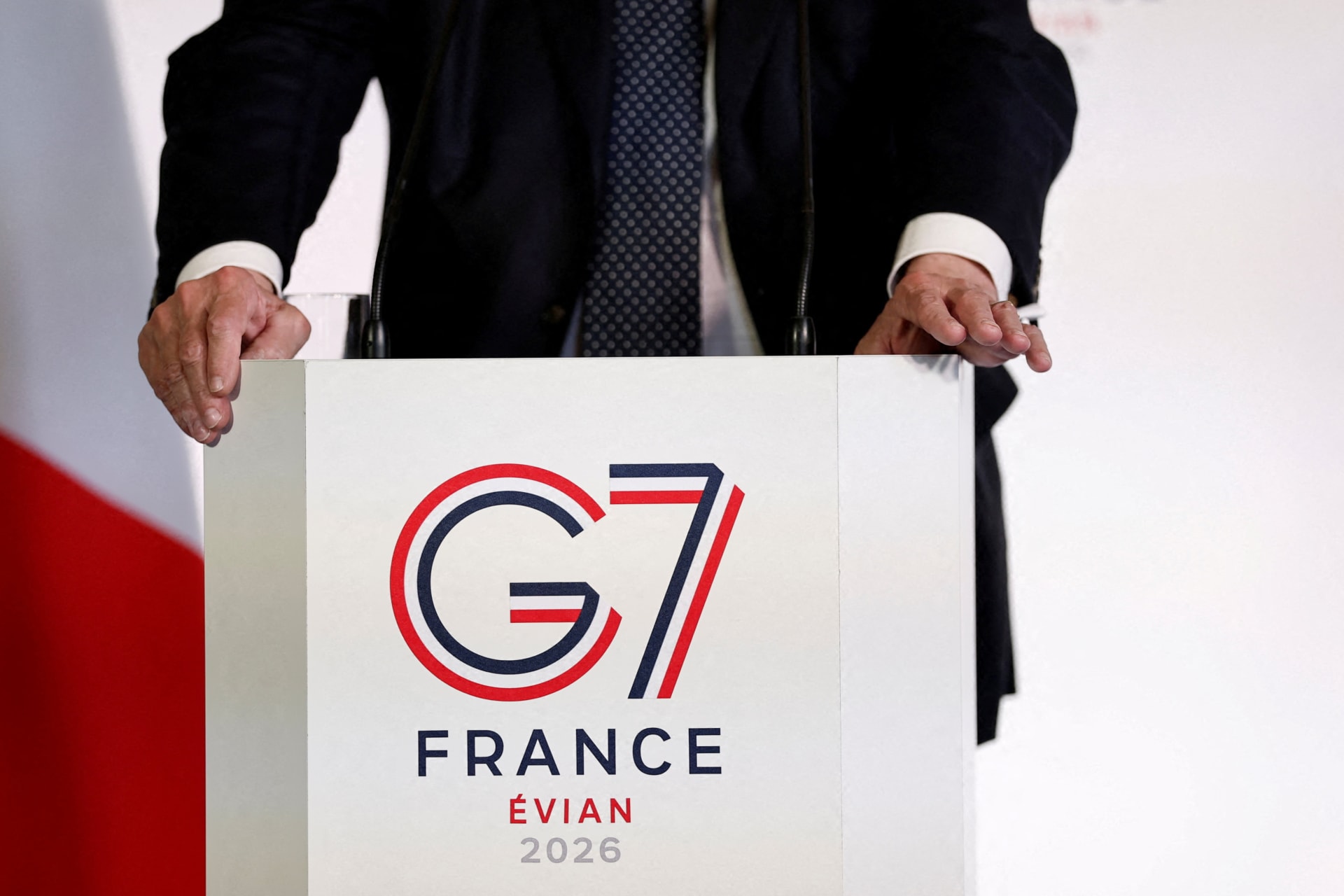 The logo of the G7 Evian summit is seen on a desk with person sitting behind it.