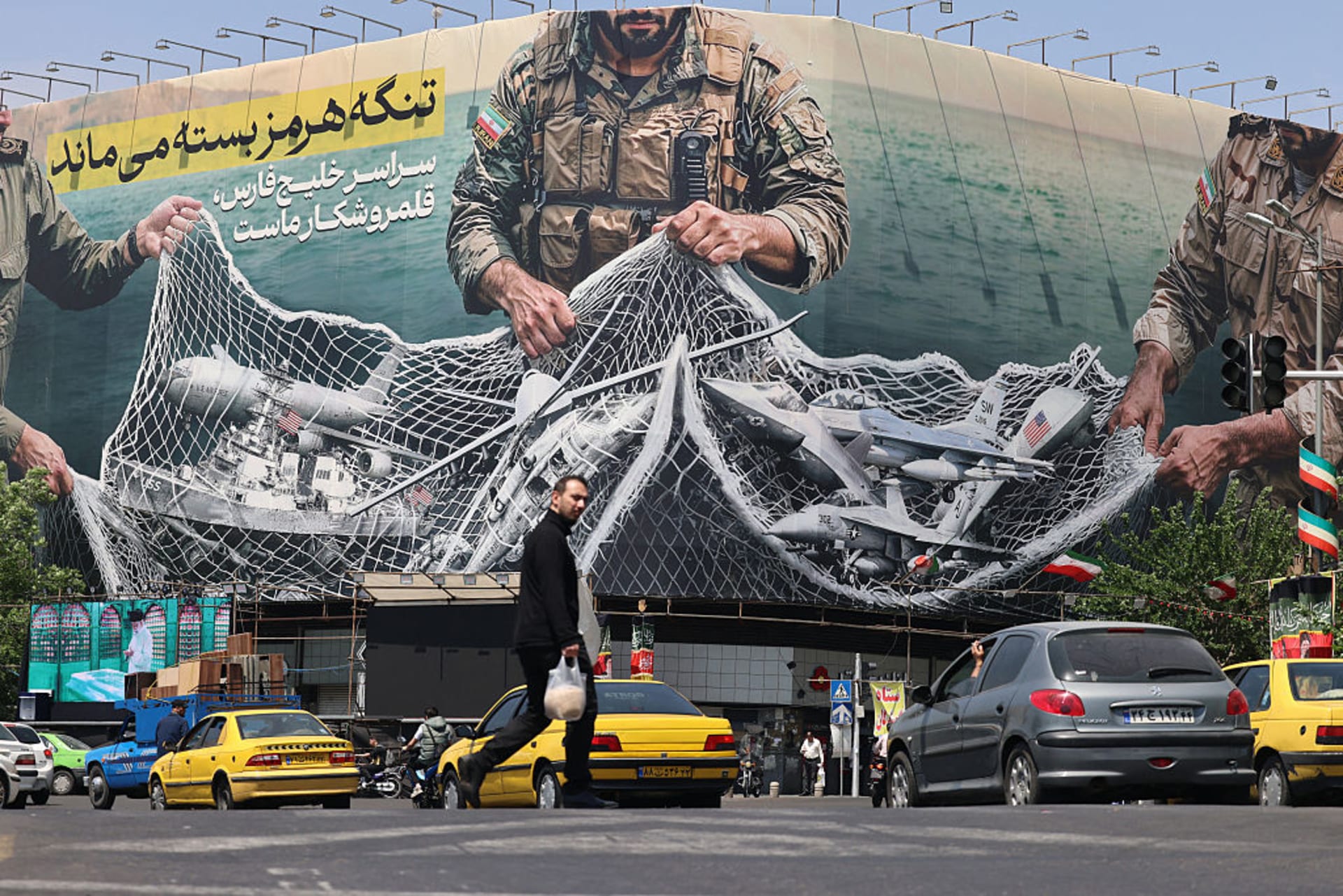 Vehicles drive past a giant billboard reading 'The Strait of Hormuz remains closed' at the Revolution Square in Tehran on April 28, 2026.