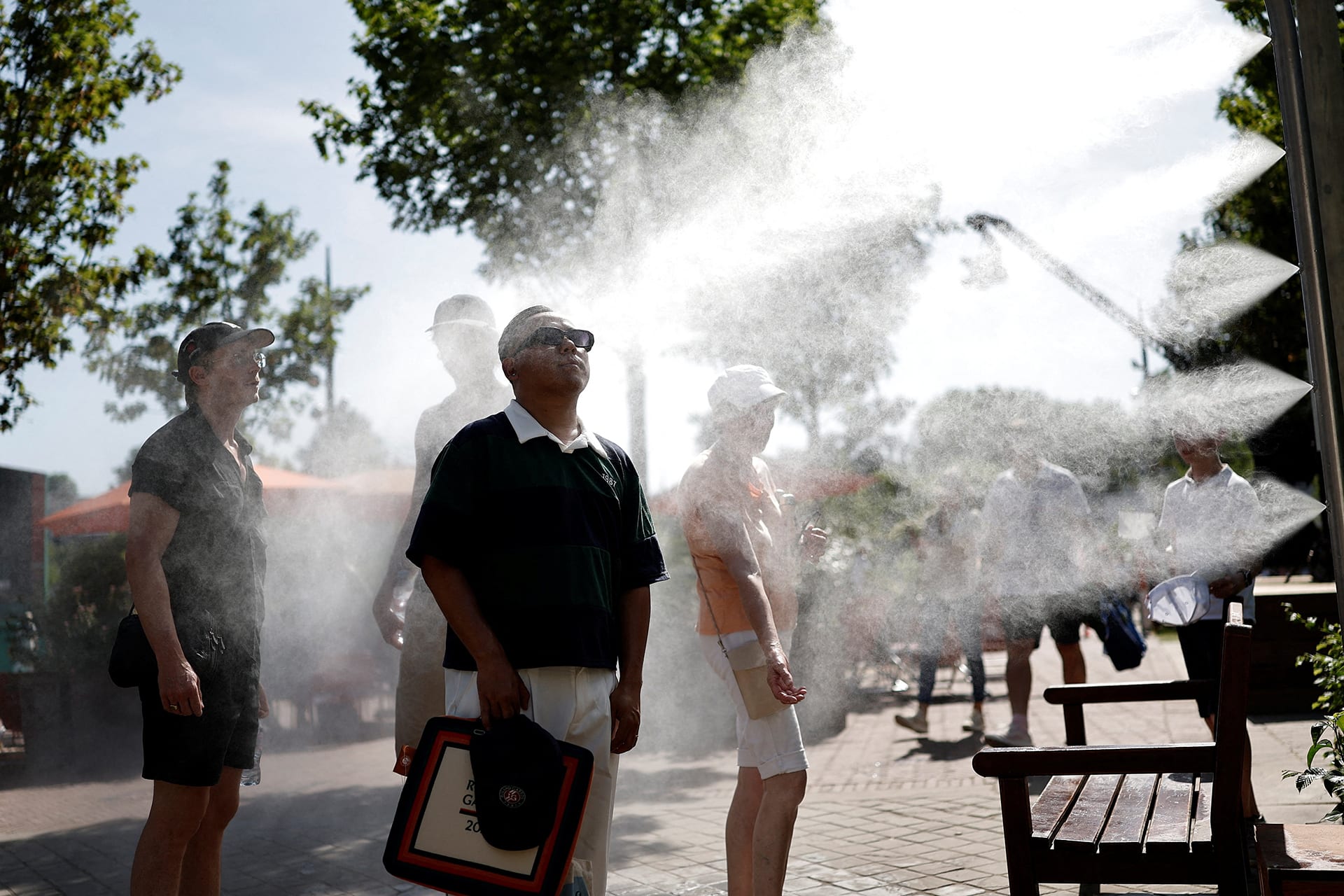 People stand to the left of the photo, and to the right is a machine that is spraying water mist onto them.