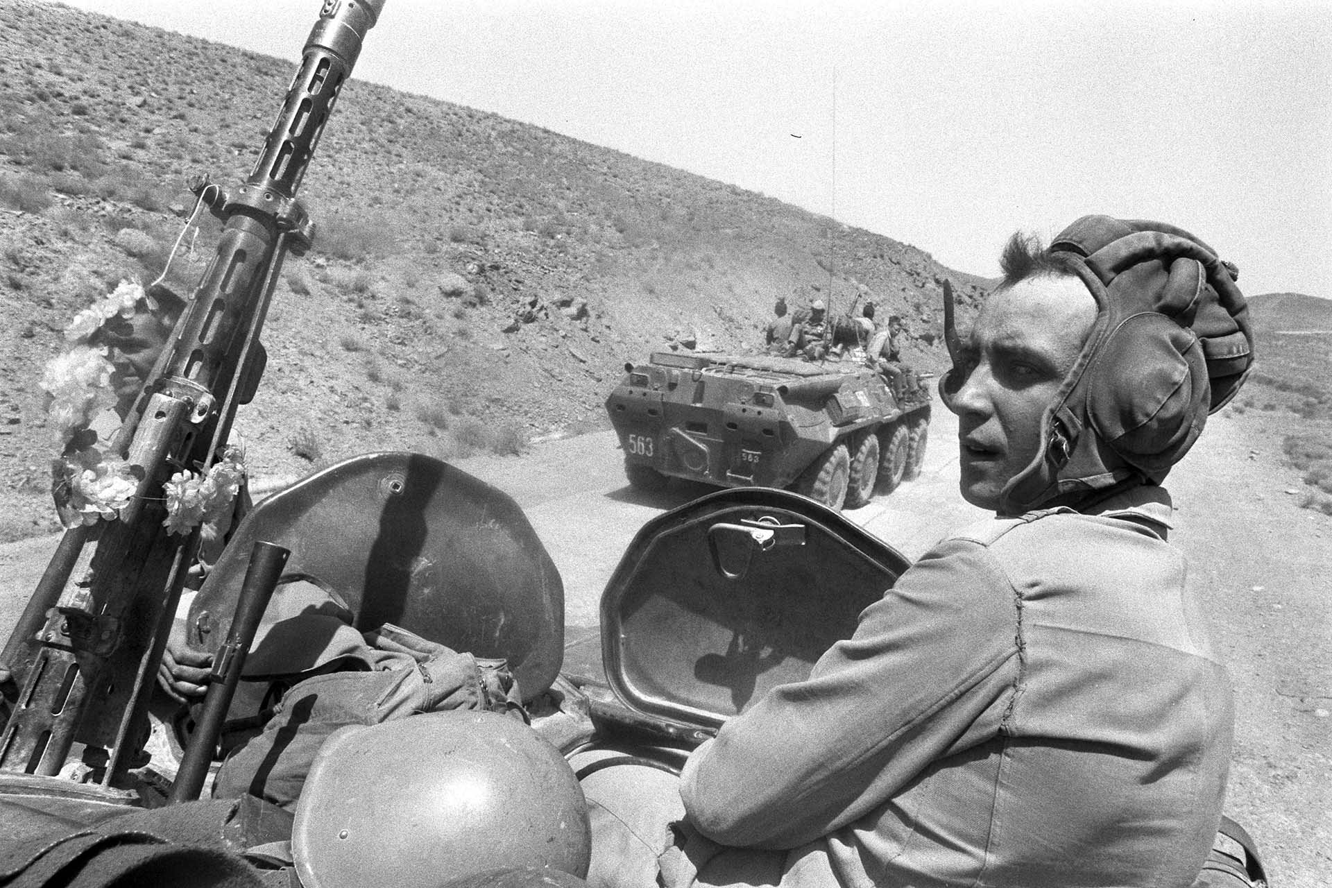 A SOviet soldier on an apc looks at the surrounding mountains as a convoy heads north to the USSR border after withdrawing from Afghanistan's SW provinces.
