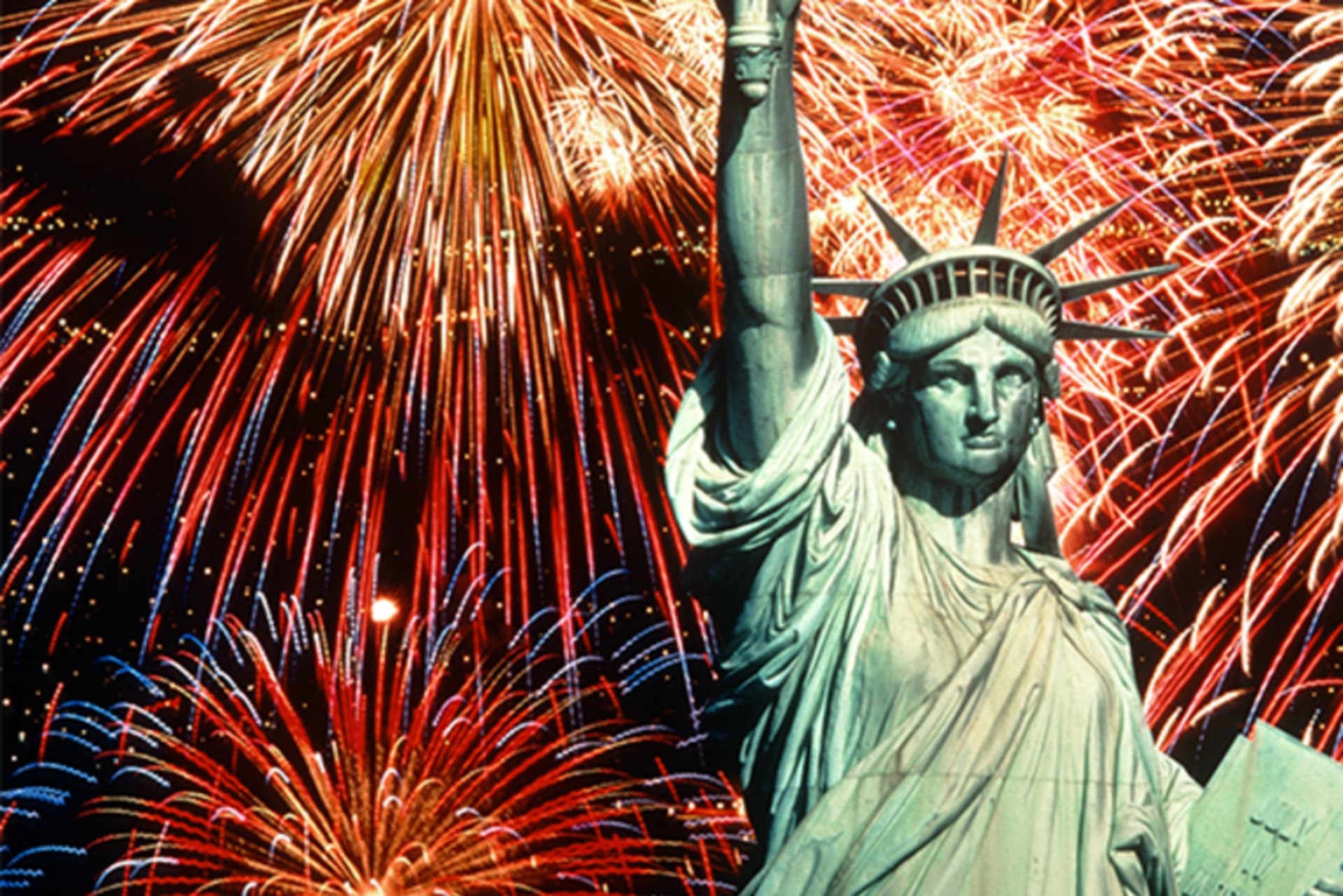 Fireworks explode behind the Statue of Liberty