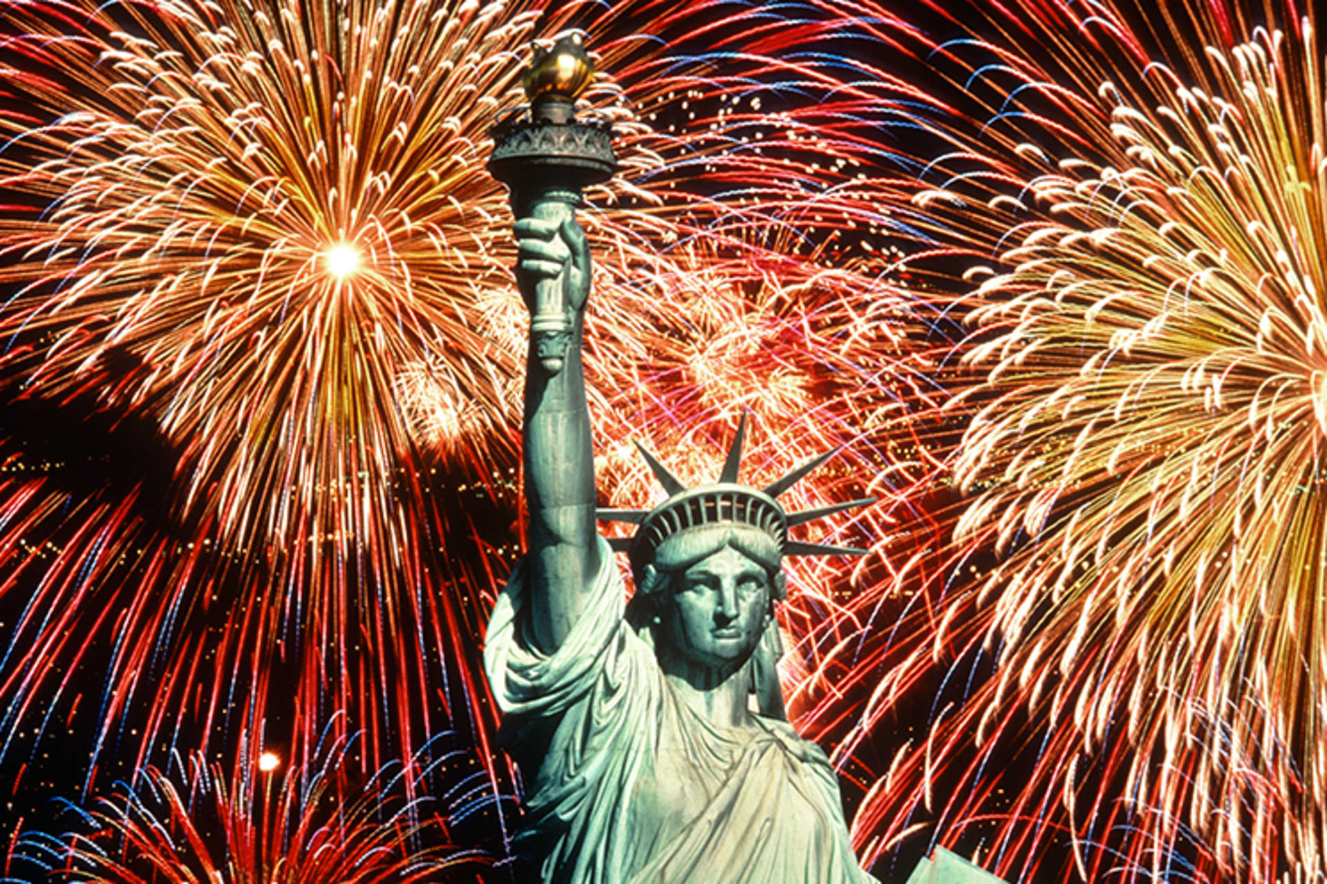 Fireworks explode behind the Statue of Liberty