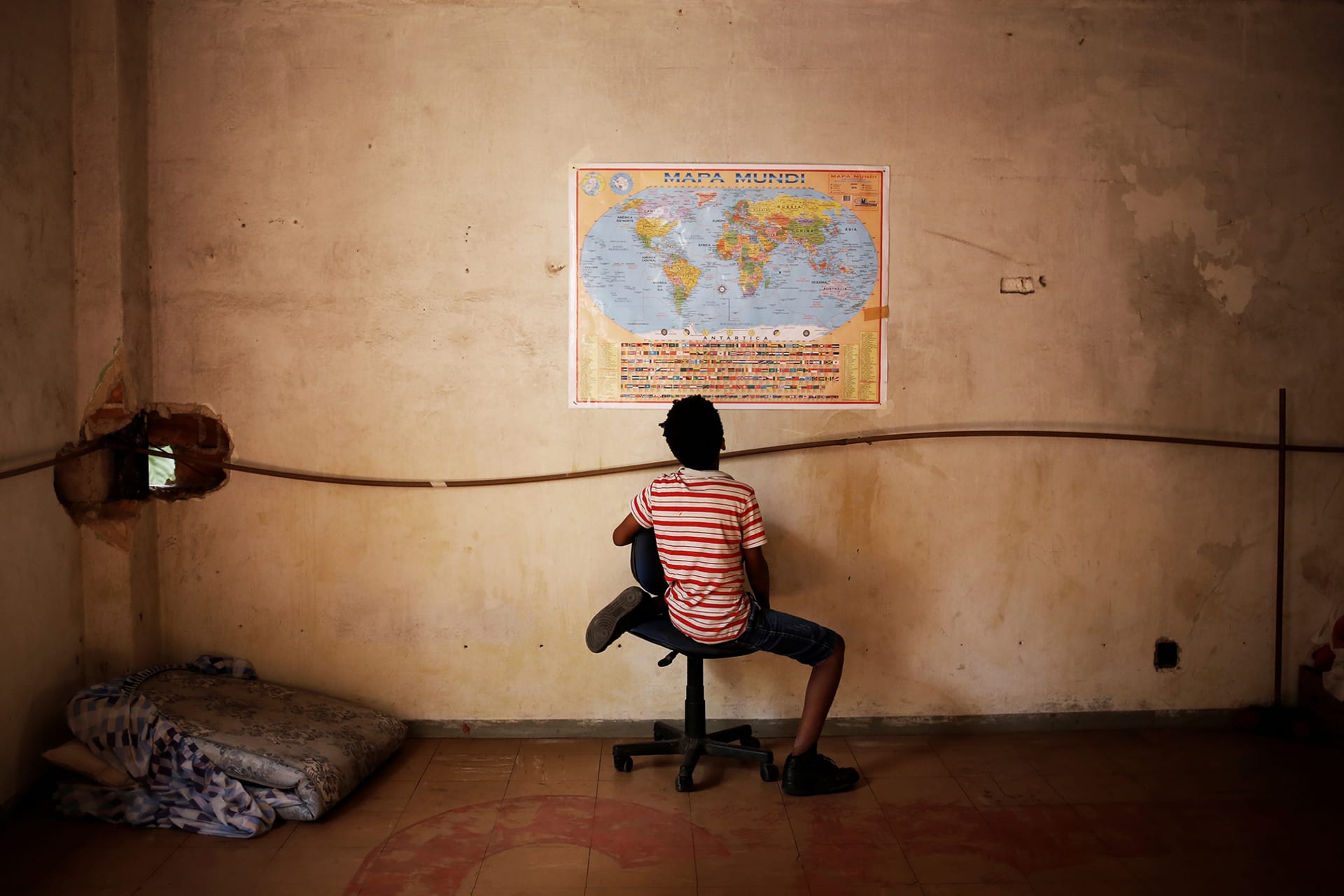 Wellington, a relative of a member of Brazil's Movimento dos Sem-Teto (Roofless Movement), looks at a world map in a vacant apartment during the occupation of an empty building in downtown Sao Paulo