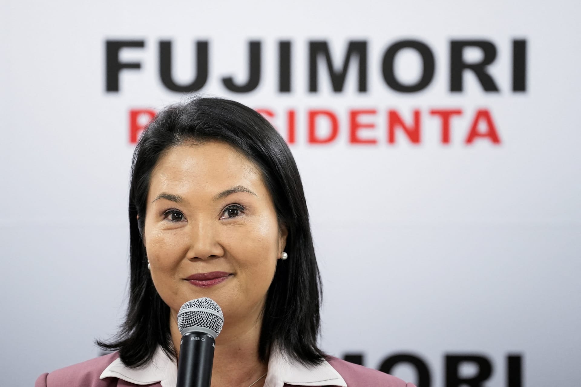 Keiko Fujimori with in front of a sign reading Fujimori Presidenta