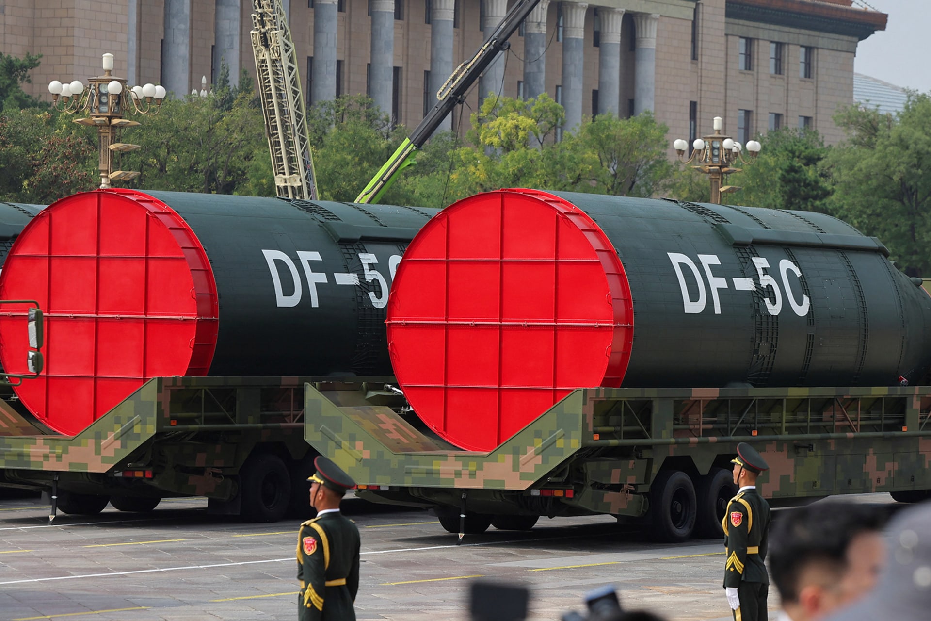 Two DF-5C nuclear missiles are displayed during a military parade as soldiers stand guard.