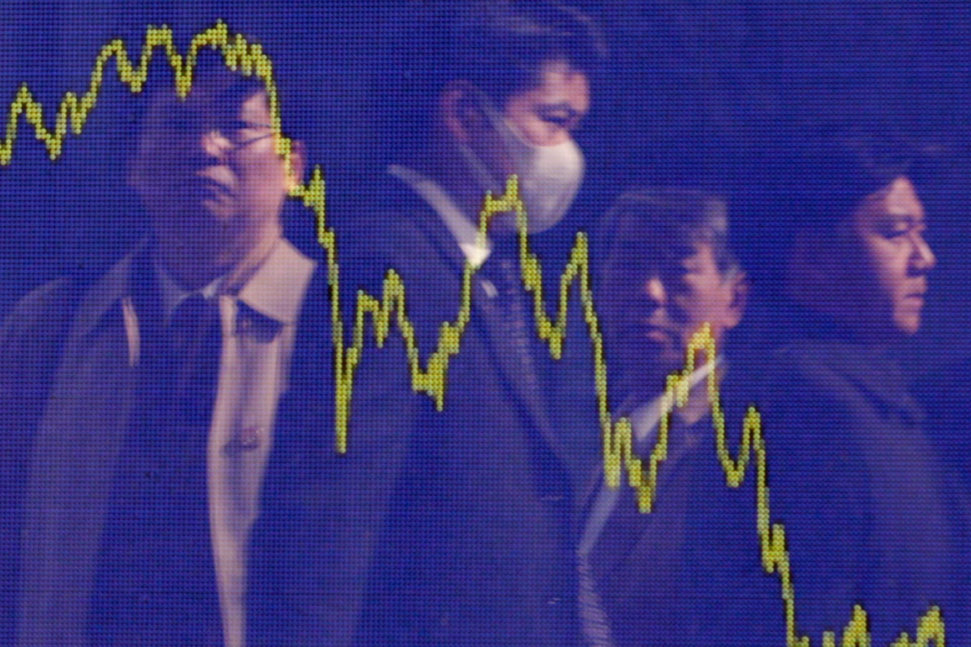 People look at a board displaying the Nikkei's 12-month average in Tokyo.