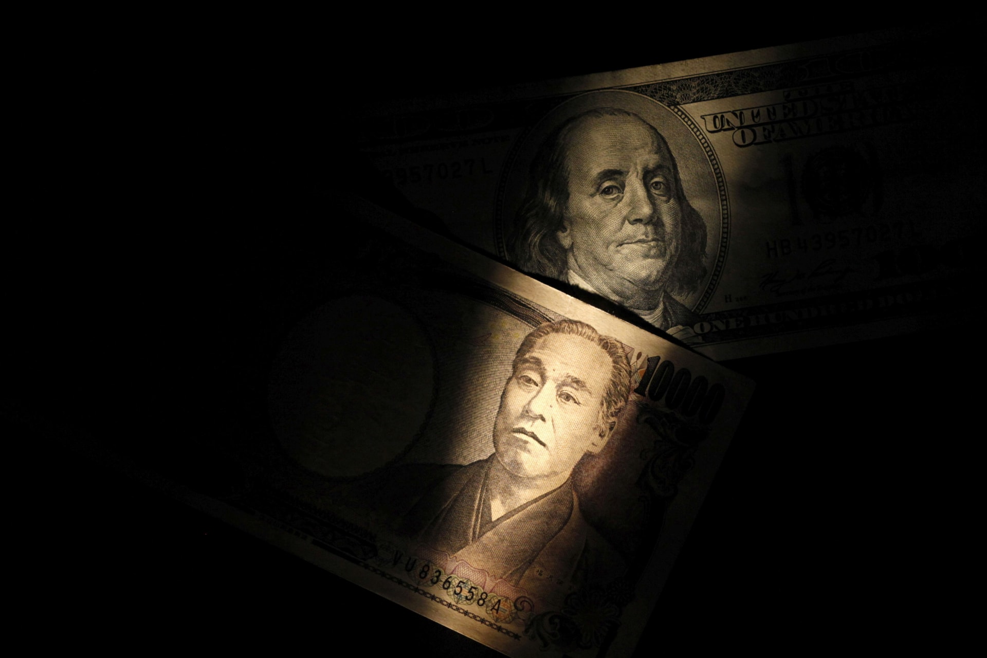 Light is cast on a U.S. one-hundred dollar bill next to a Japanese 10,000 yen note in this picture illustration shot February 28, 2013.