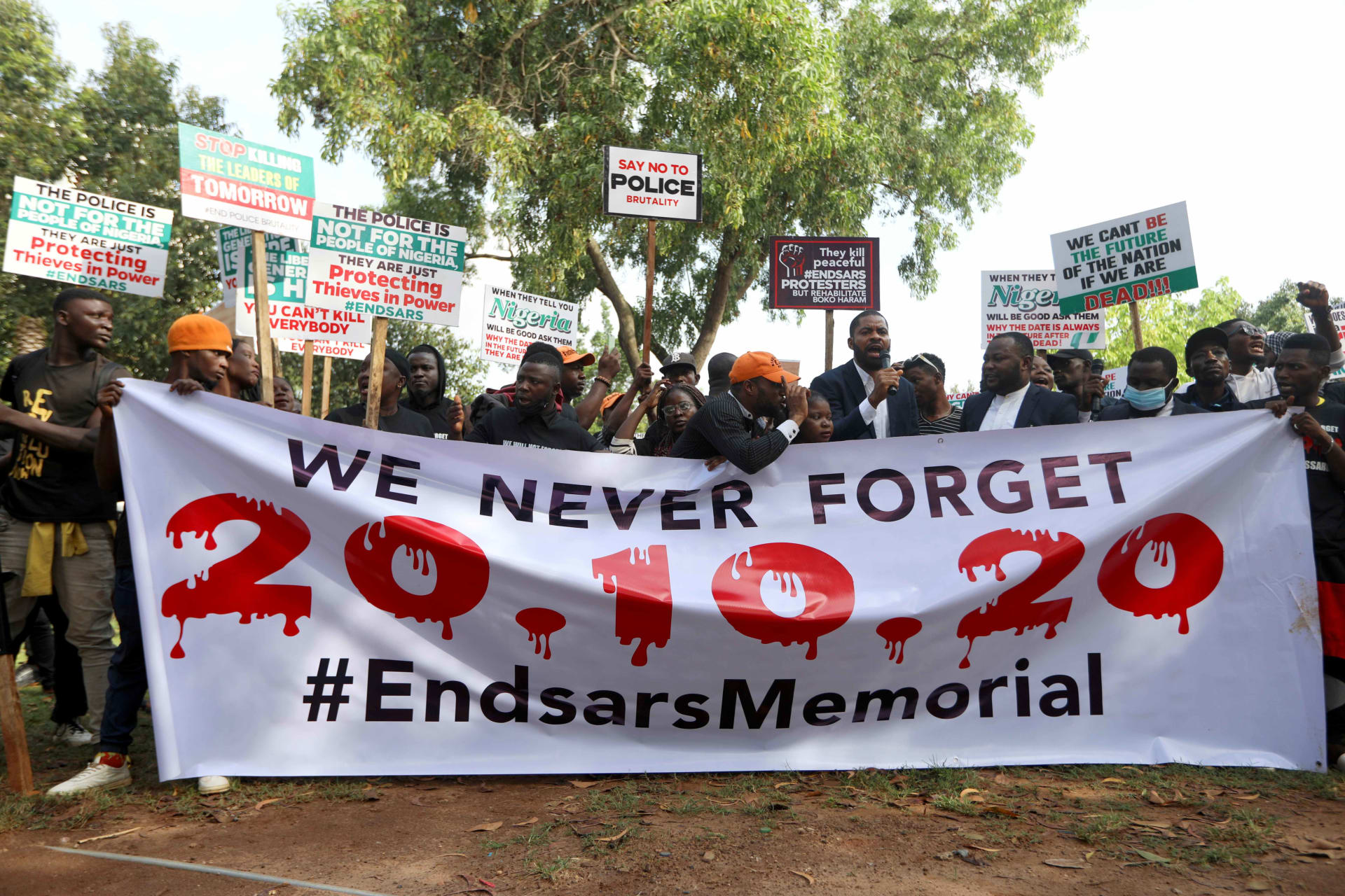 <p>Protestors hold a poster and placards as Nigerians mark the one-year anniversary of the EndSARS anti-police brutality protest in Abuja, Nigeria, on October 20, 2021.</p>
