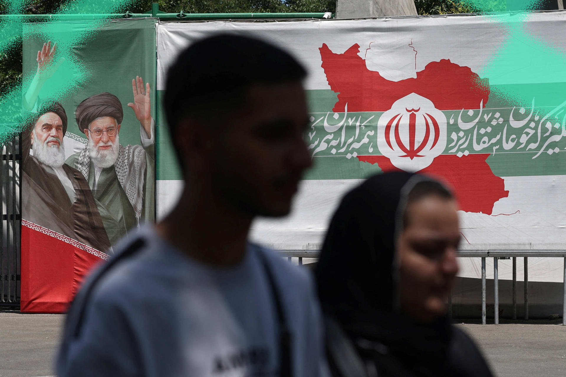 People walk past a banner with pictures of the late leaders of the Islamic Republic on a street in Tehran, Iran on June 9, 2026.
