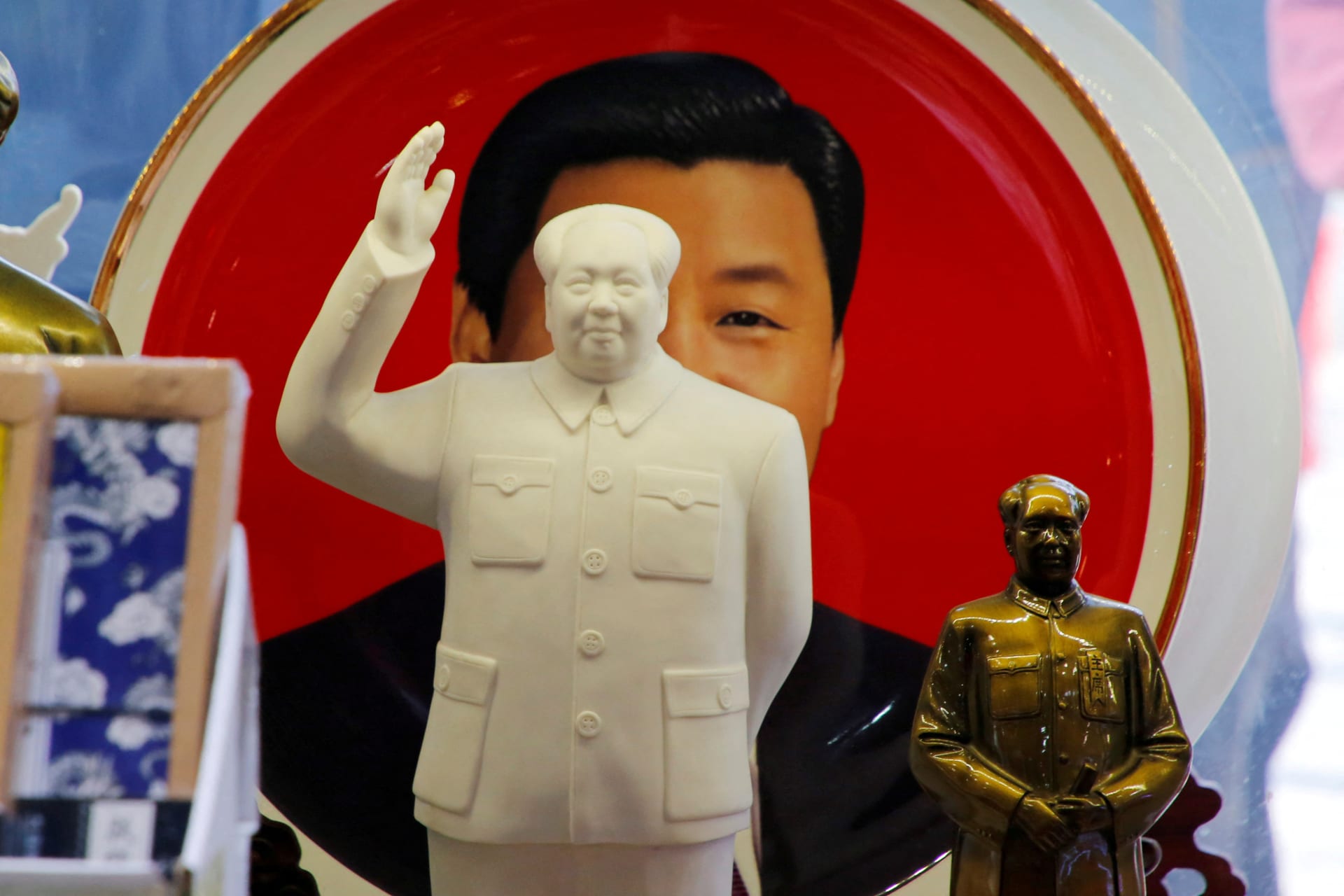 FILE PHOTO: Sculptures of the late Chinese Chairman Mao Zedong are placed in front of a souvenir plate featuring a portrait of Chinese President Xi Jinping at a shop in Beijing