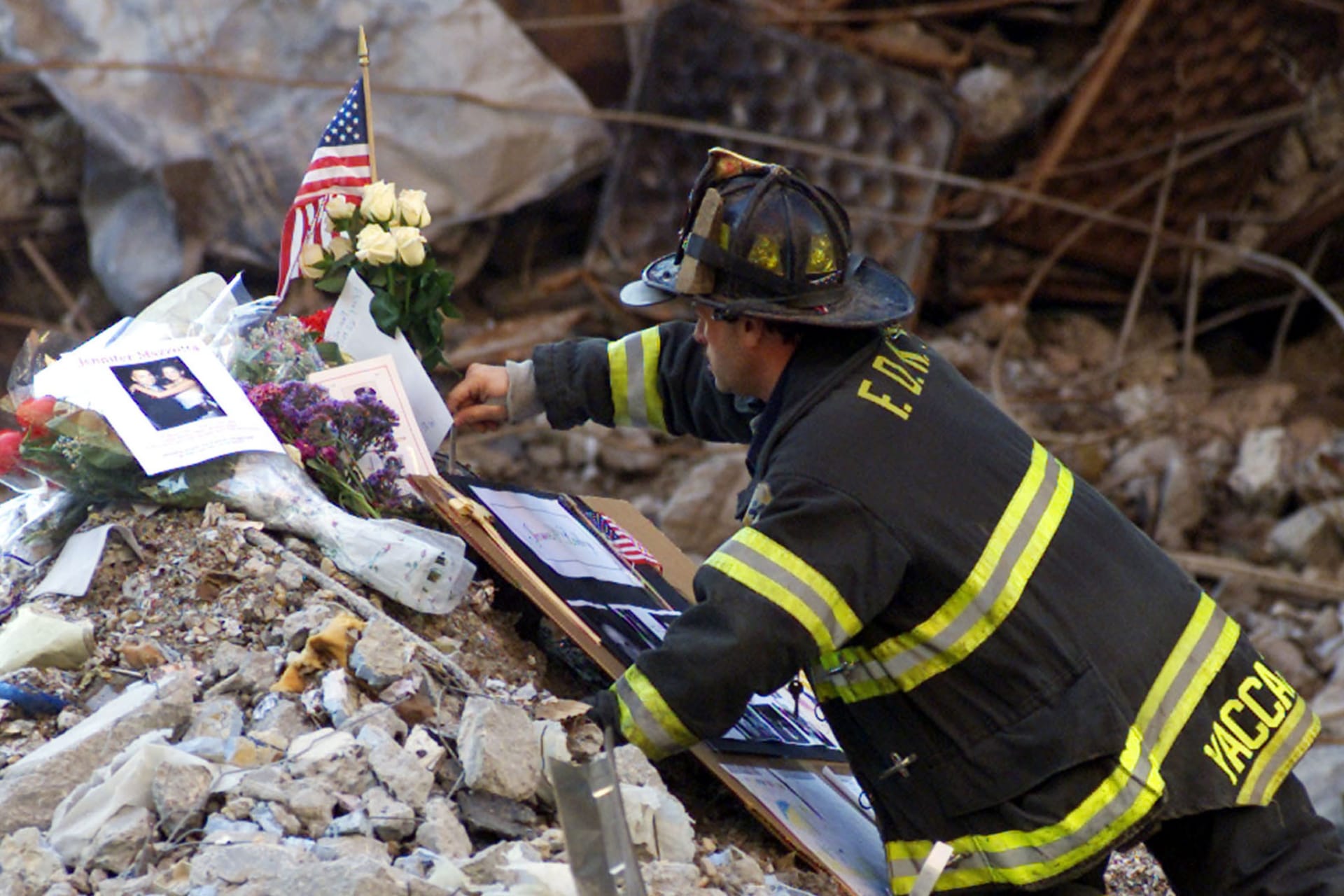 A New York City firefighter places flowers and mementos from family members of the victims of the World Trade Center disaster amidst the wreckage following a memorial service for the victims of the September 11 attack at the site in New York on October 28, 2001.